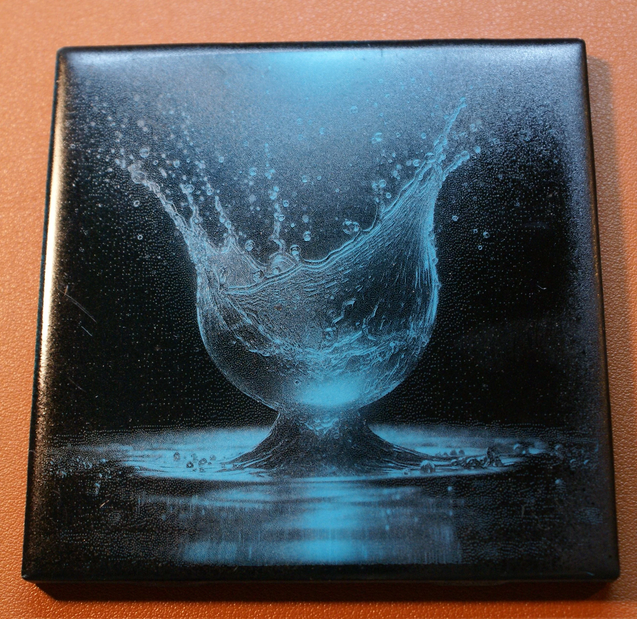 Black box with a blue-tinted splash of water forming a glass of water with water droplets splashing out.