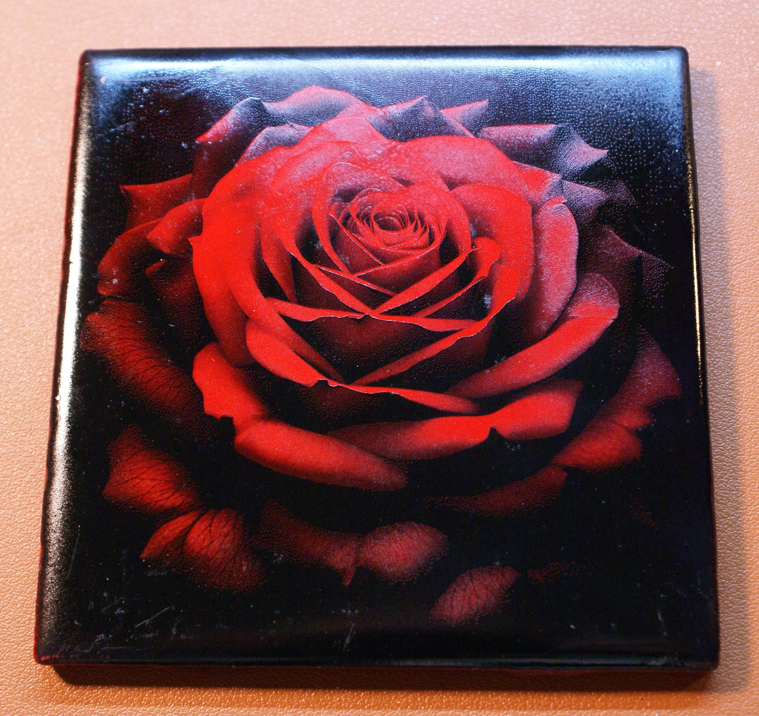 A square box with a detailed image of a red rose on the lid.