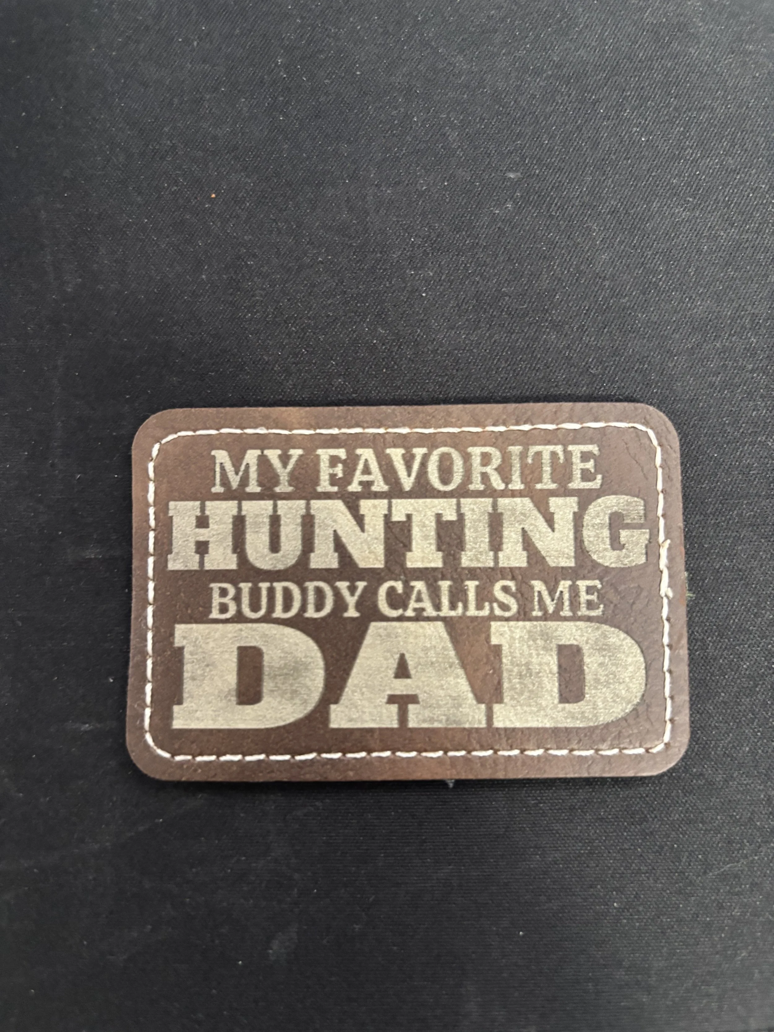 A brown patch with white stitching that reads, 'My favorite hunting buddy calls me dad'.