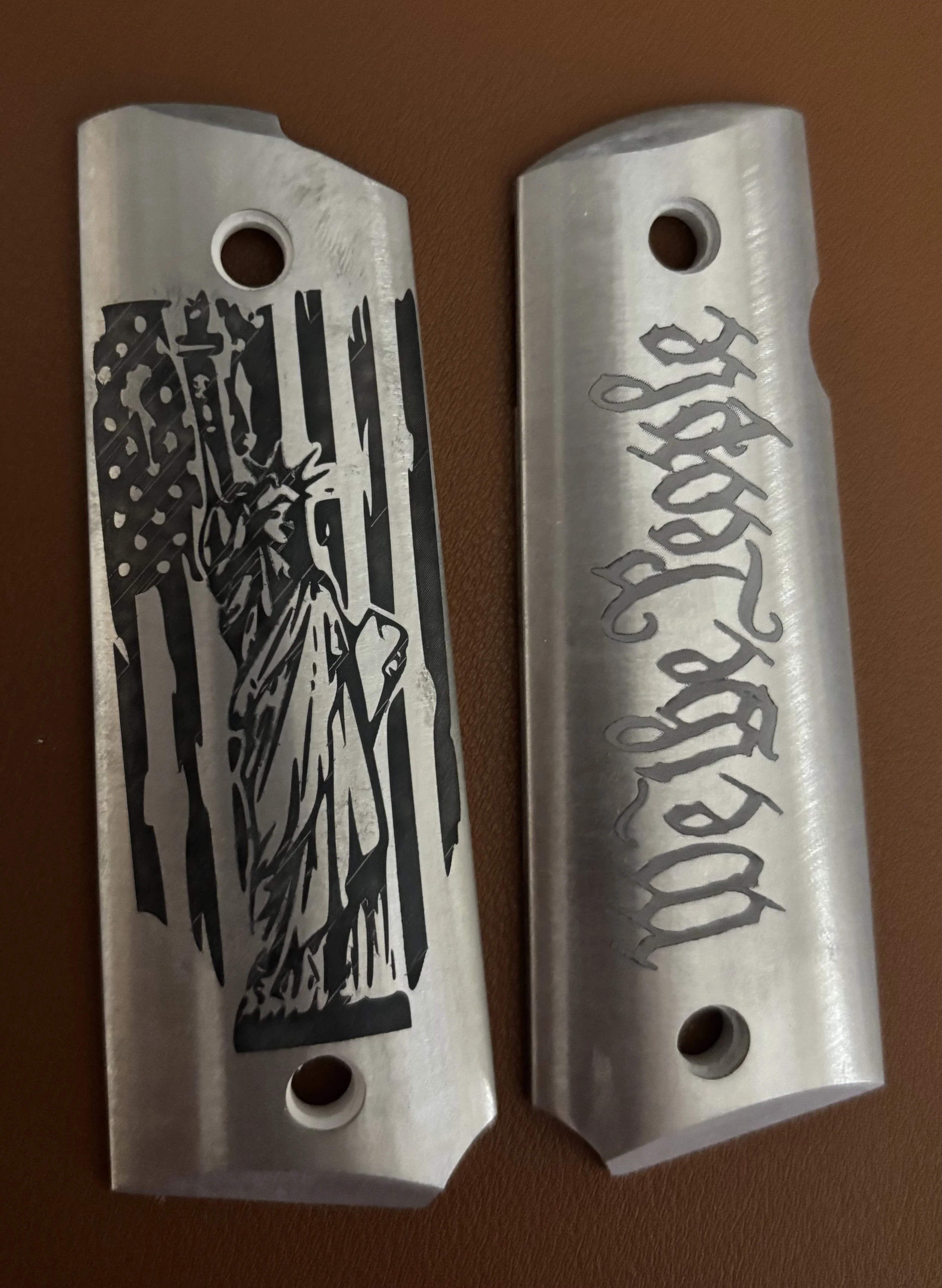 Two metallic objects with engraved designs, one featuring a depiction of the Statue of Liberty and the other with stylized text.