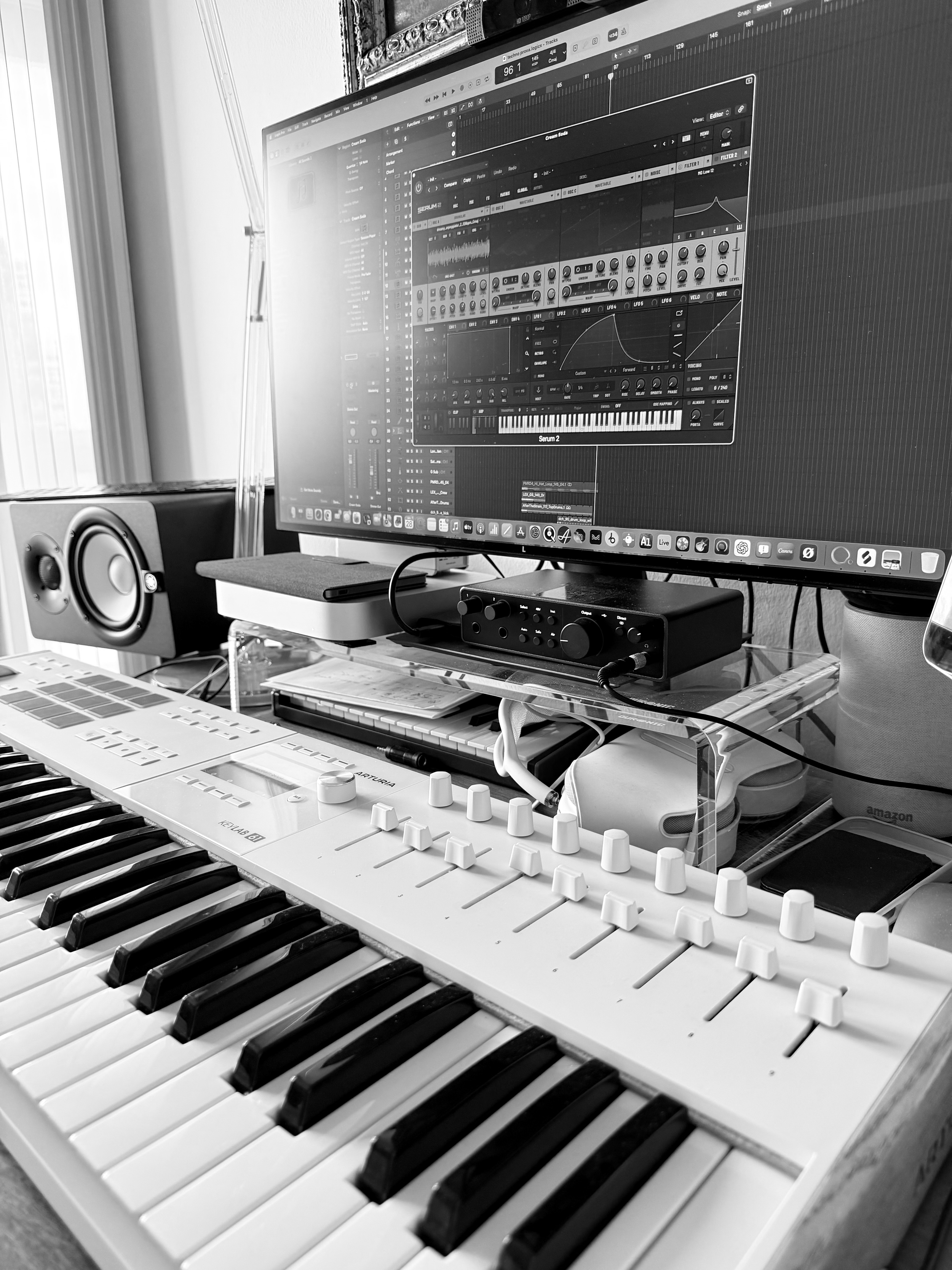 Tastiera musicale bianca con tasti neri e bianchi, sopra un setup di apparecchiature audio e software di produzione musicale sul monitor dello schermo, in un ambiente di studio.
