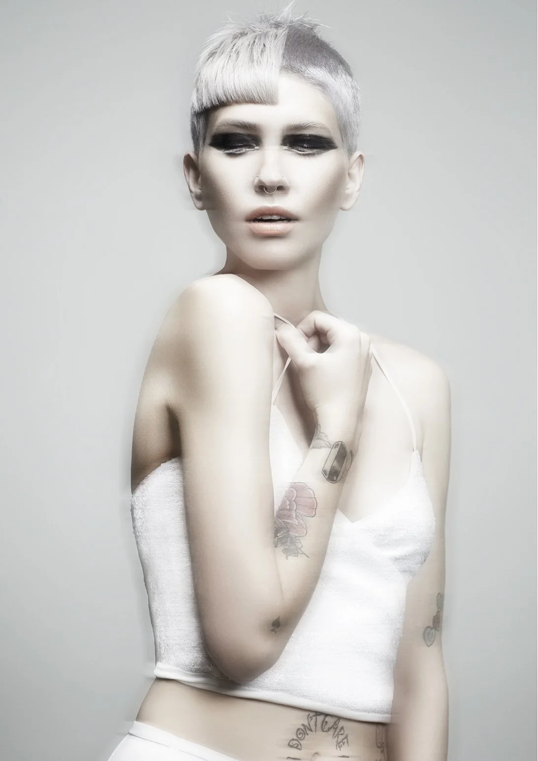 Fashion model with red and purple layered hair, wearing dark lipstick and a black sleeveless top, in a studio setting.