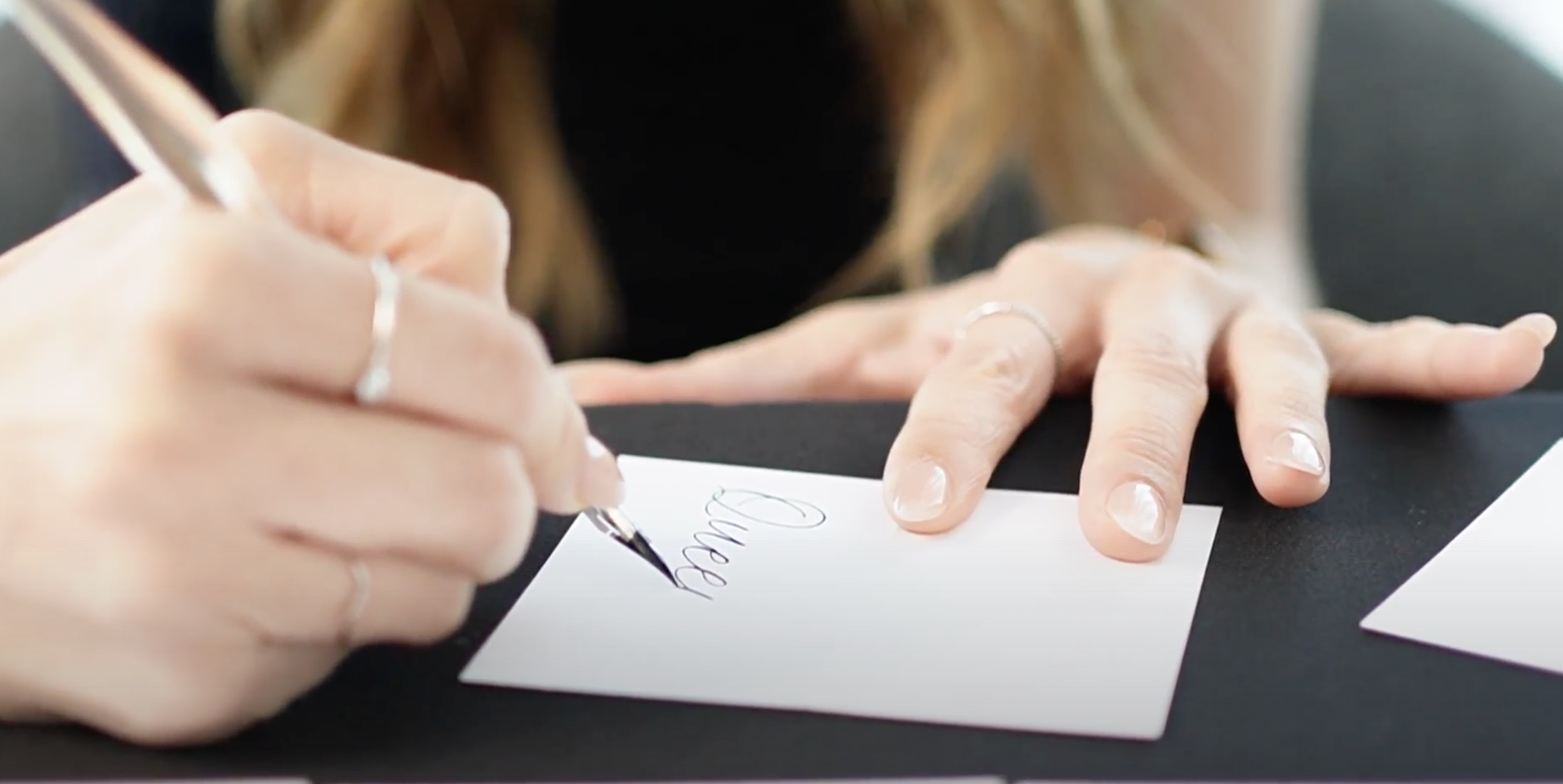 Person signing a card with the word 'Thank' written on it.