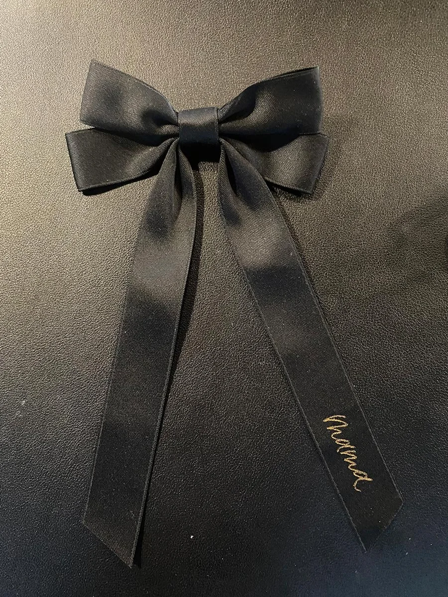 Black gift box with a black satin ribbon tied in a bow, with a black tag that has 'Thanks!' written in gold.