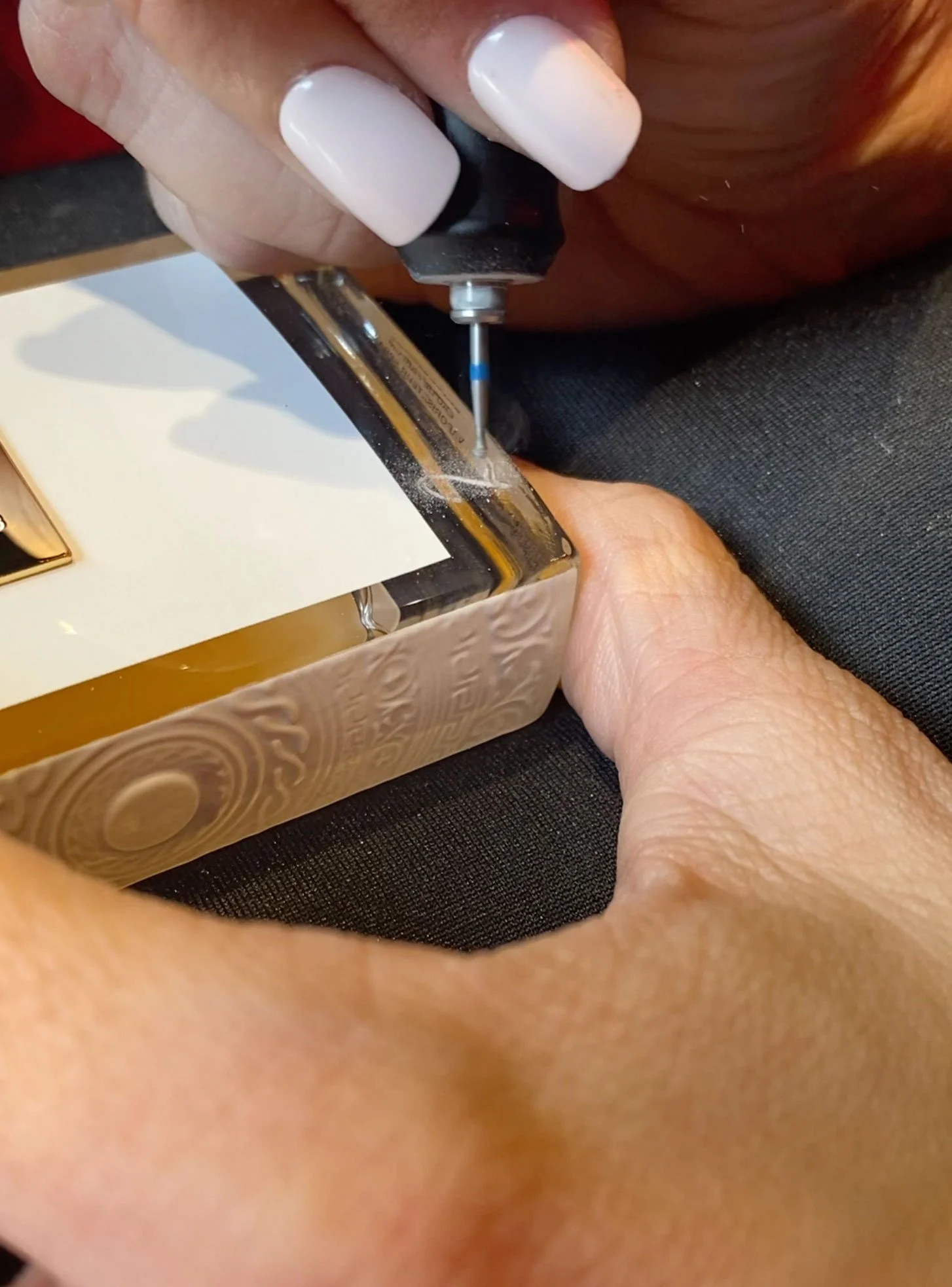 Person holding a jewelry box while using a precision screwdriver to perhaps open or repair it.