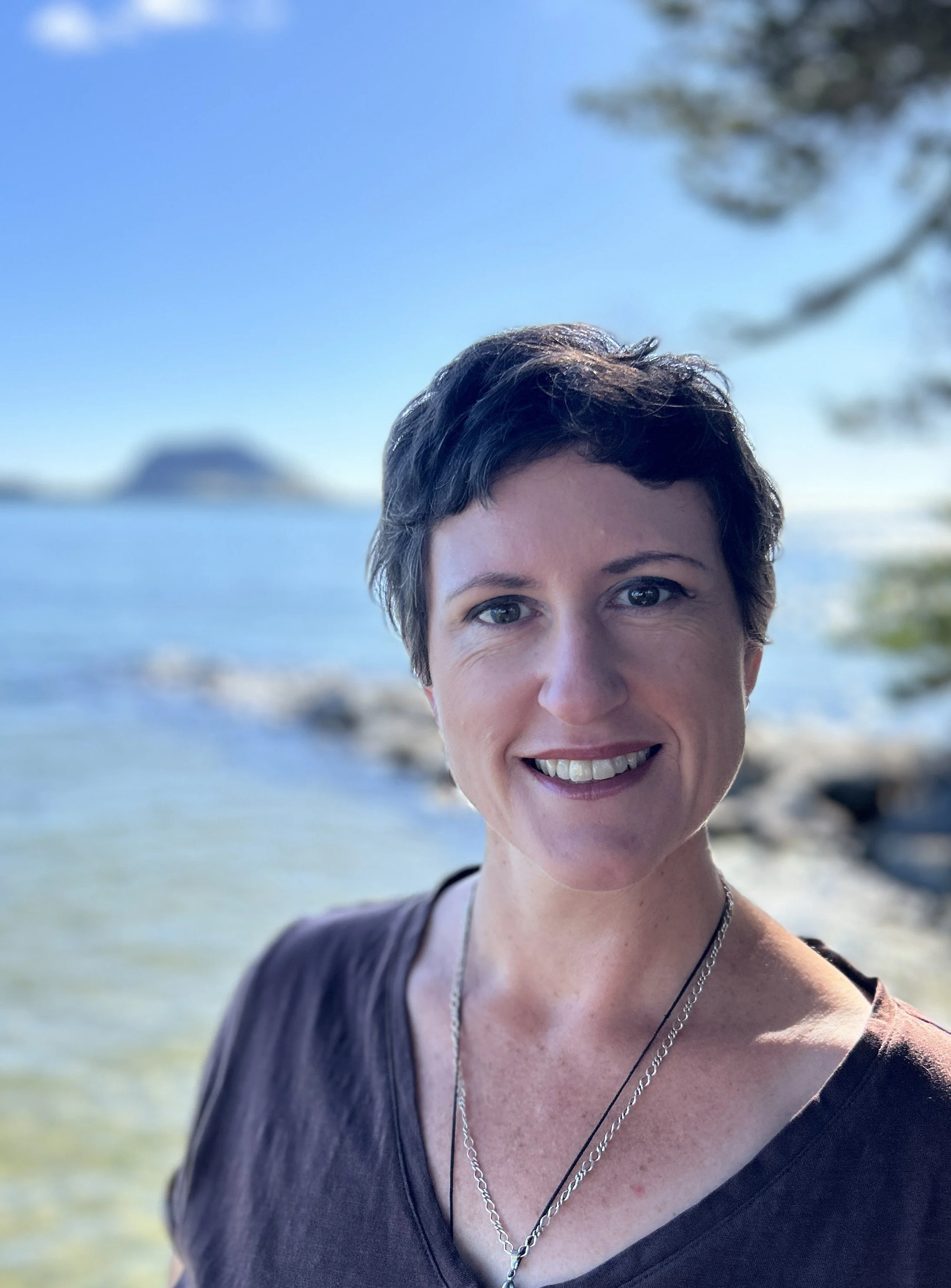 A pciture of Barbara Mead standing in the natural environment with a seascape behind her.