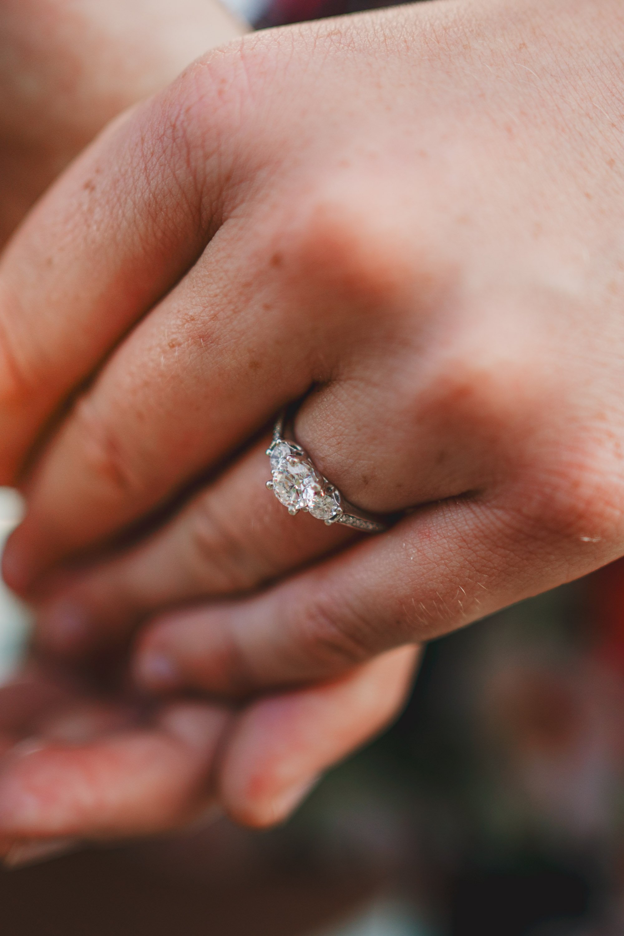 Close-up of a hand with an engagement ring featuring multiple diamonds.