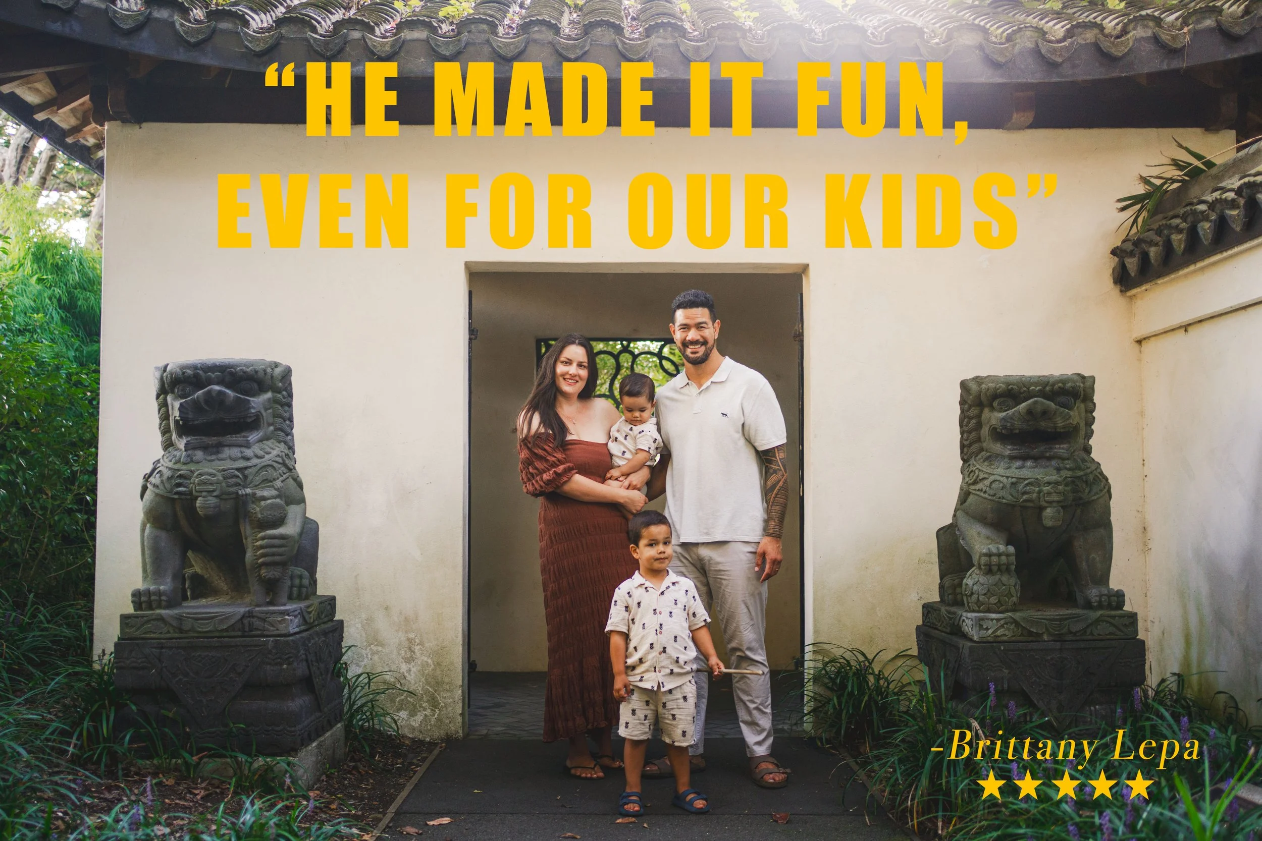A family of four, including a woman, a man, a young boy, and a baby, standing together outside a building with traditional Asian lion statues on either side. The image features a quote in bold yellow letters: "He made it fun, even for our kids," attr