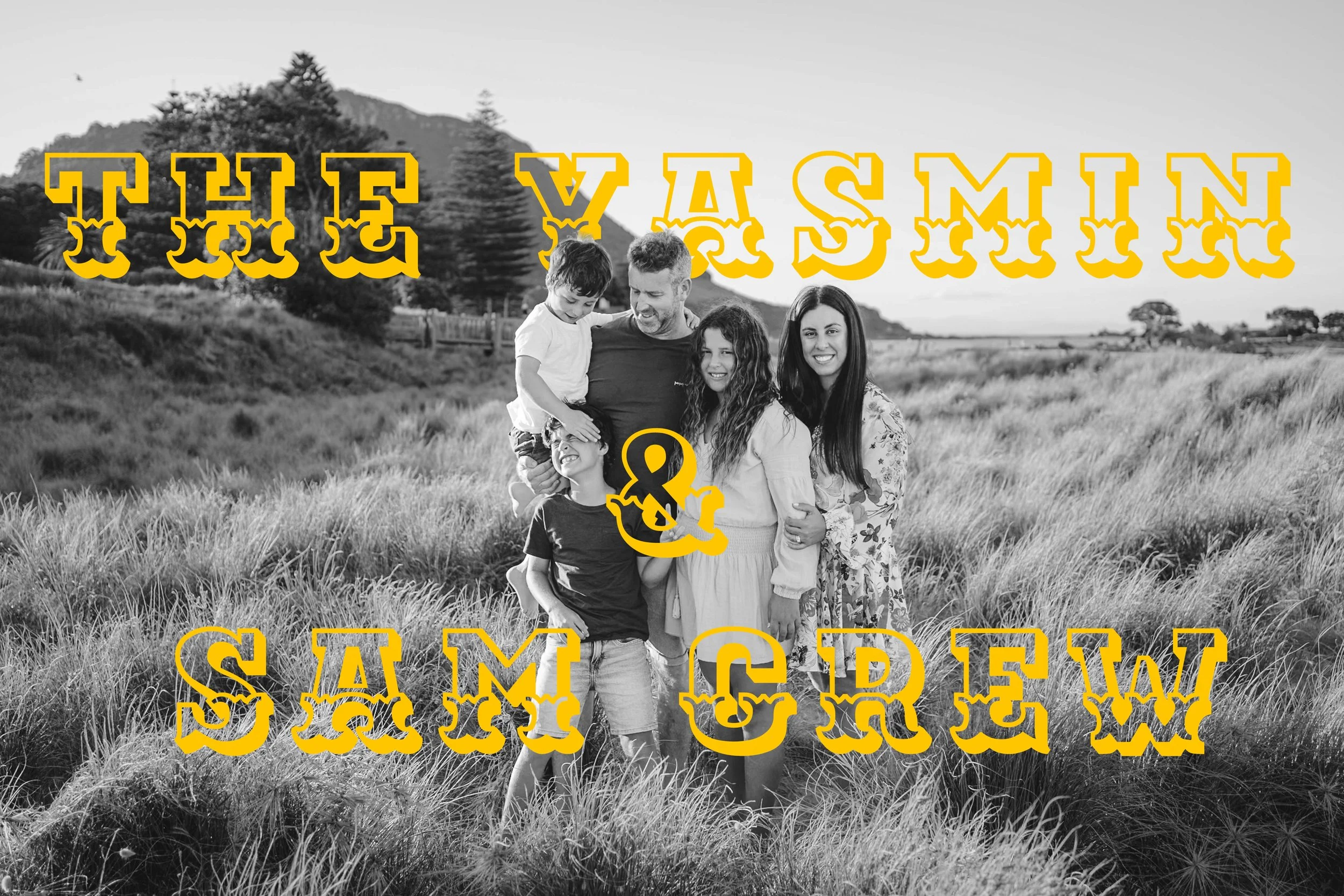 A black-and-white photo of a family of five standing in a field with tall grass, with hills and trees in the background. The photo has bold yellow text overlay reading "The Yasmin & Sam Crew."