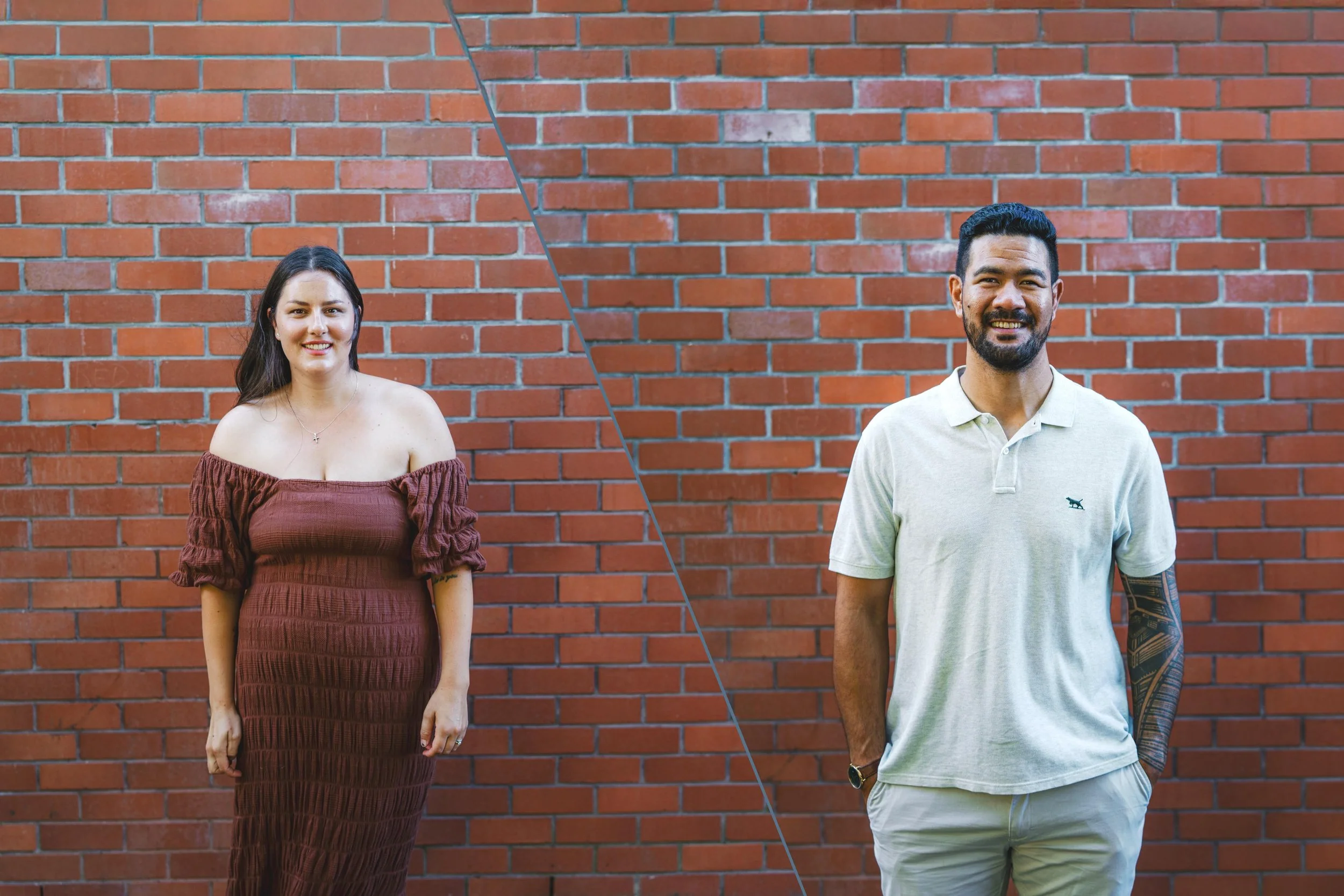 A woman in a brown off-the-shoulder dress and a man in a light-colored polo shirt and shorts standing in front of a red brick wall.