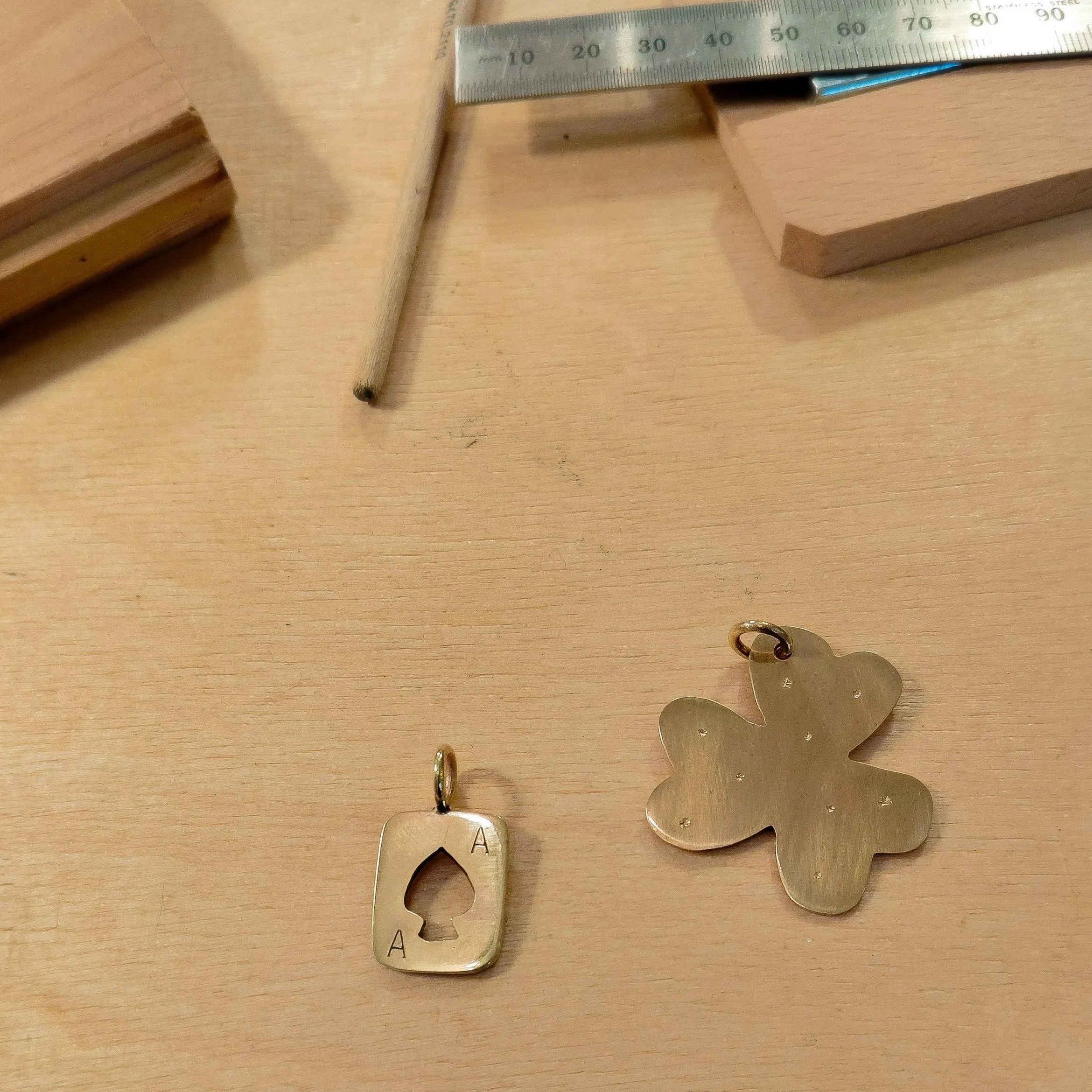 Close-up of a metal ruler and several metallic cutouts of various shapes on a wooden surface.