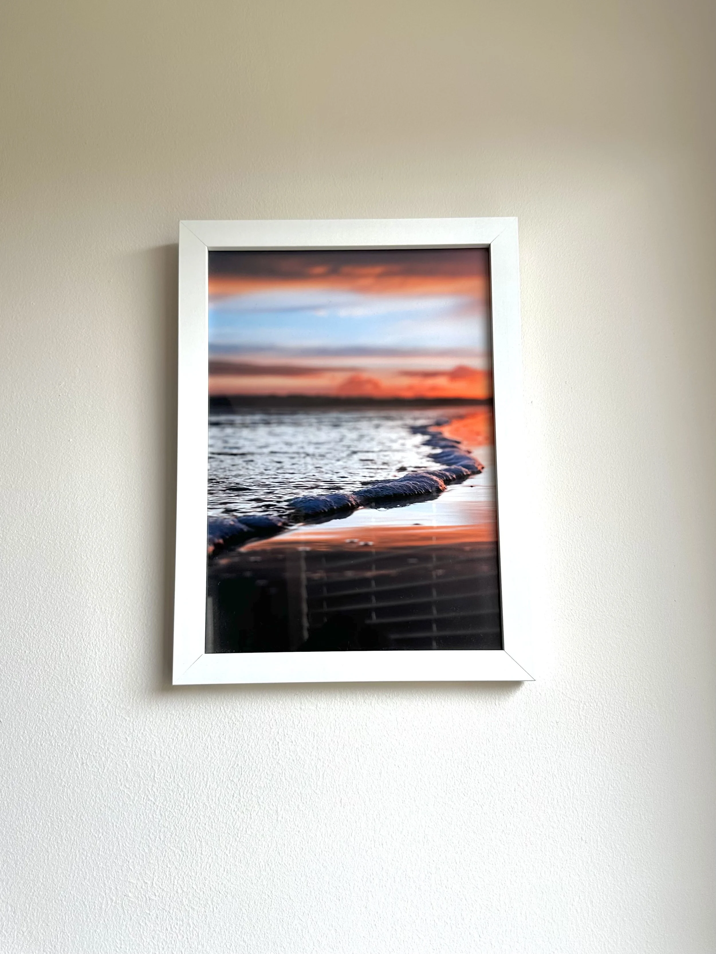 Framed sunset photograph of a beach with calm waves on the shore.