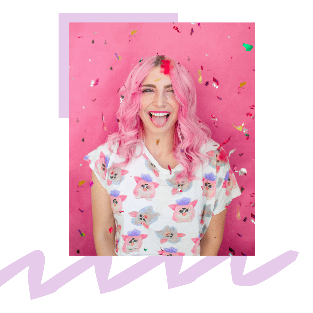 Girl with pink hair celebrating with confetti in front of a pink background.