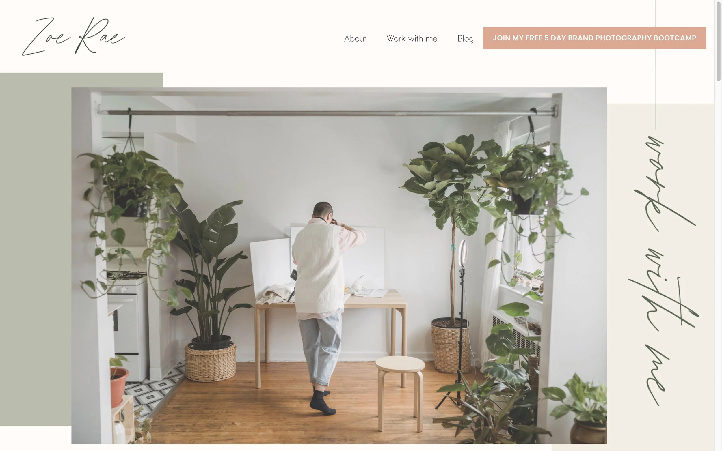 Interior of a bright room with large green plants, a wooden table, and a person taking photos of canvases with gardening tools and camera gear.