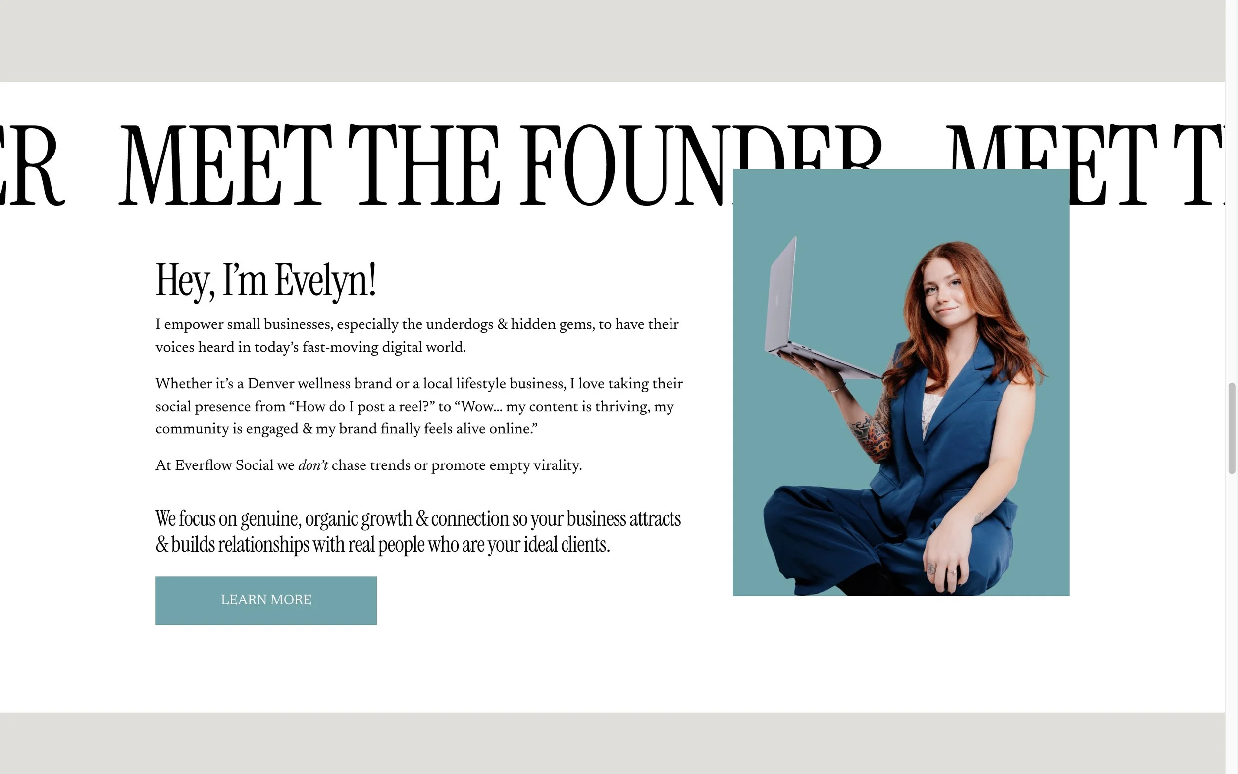 A woman with red hair, wearing a blue outfit, holding a laptop in her right hand, sitting with one elbow resting on her knee, against a light blue background.