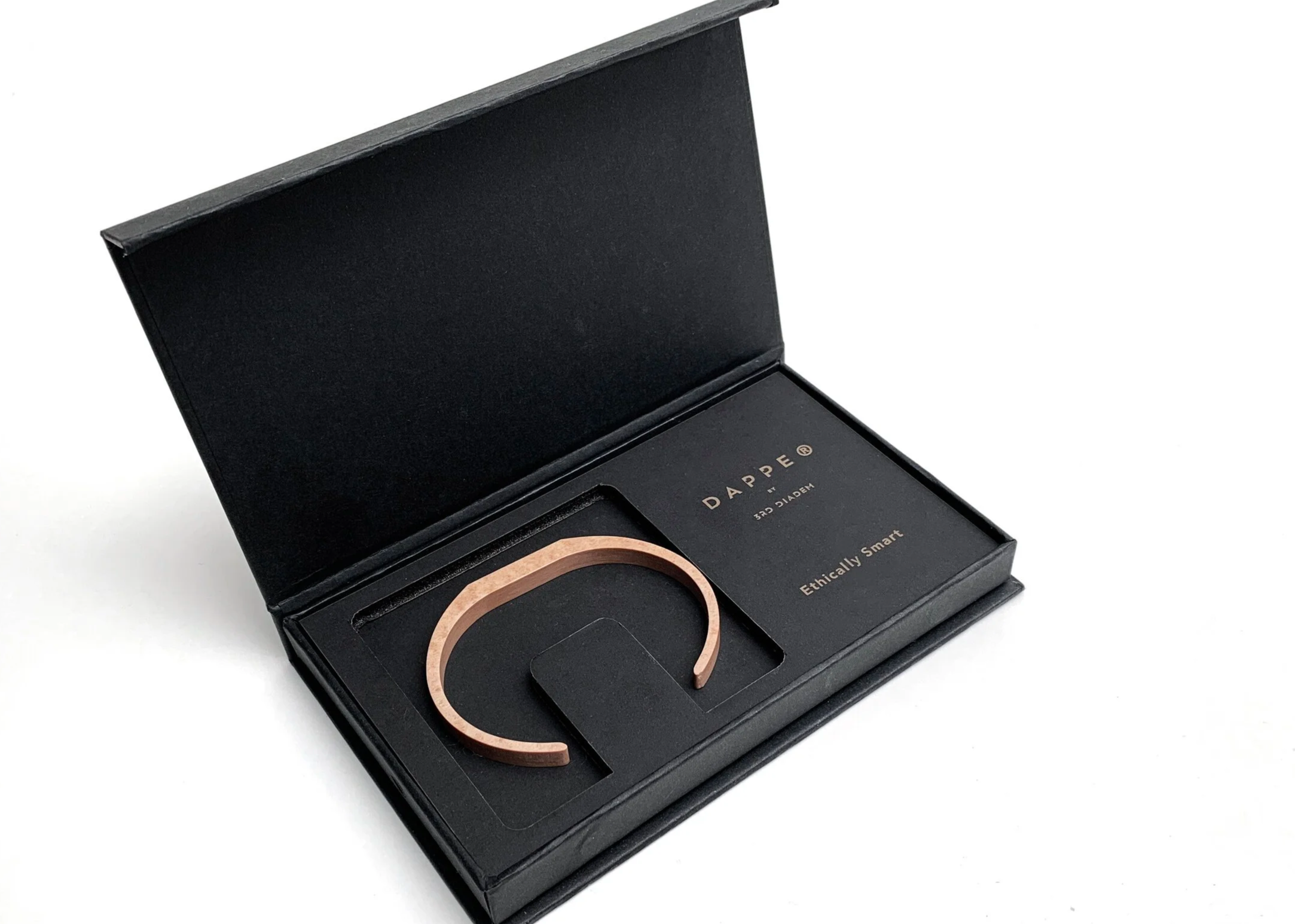 Open black box with a japanese designer's compressed paper bracelet inside, accompanied by a card labeled 'DAPPÉ' and 'Ethically Smart'.