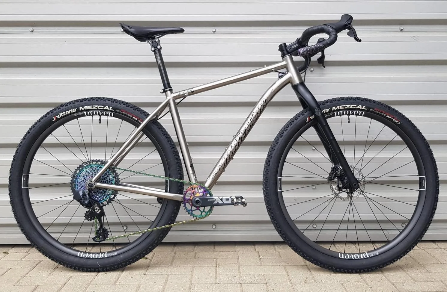 A Smokestone Mr Harry Bikepacking Bike with black tires and suspension fork, parked against a metal garage door.