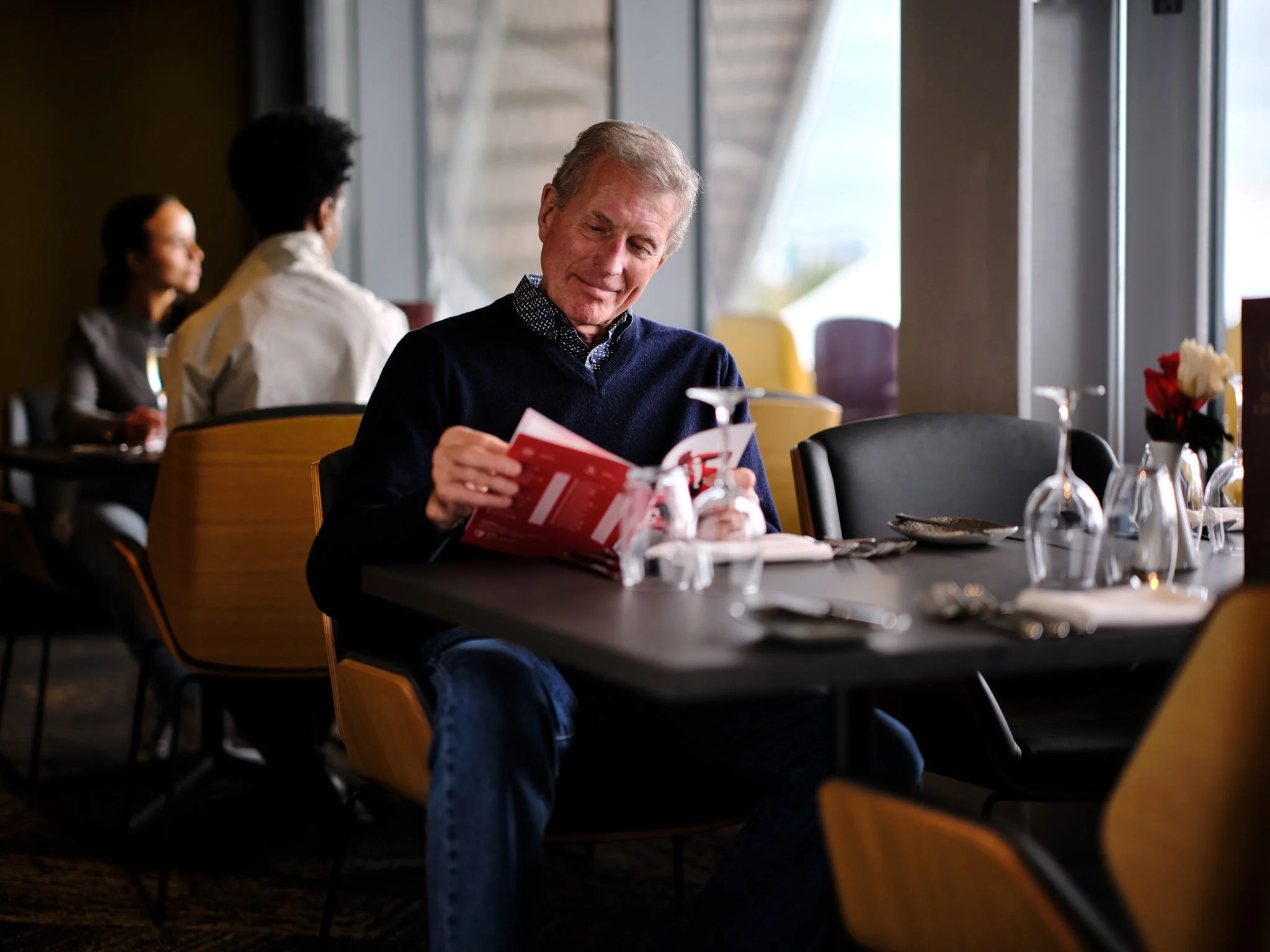 Restaurant Bar at Brentford FC Gtech Community Stadium with fan looking at match day programme, photography by Premier Stadium Images
