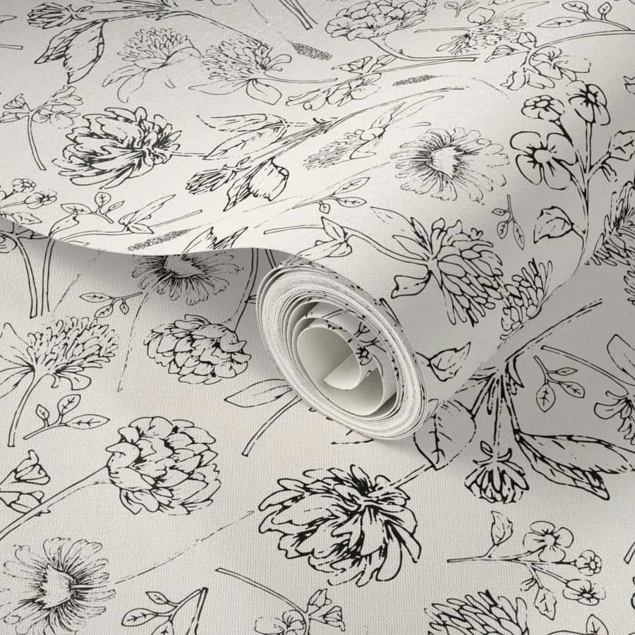 Black and white floral wallpaper roll unrolled on a flat surface, showing detailed hand-drawn line work.