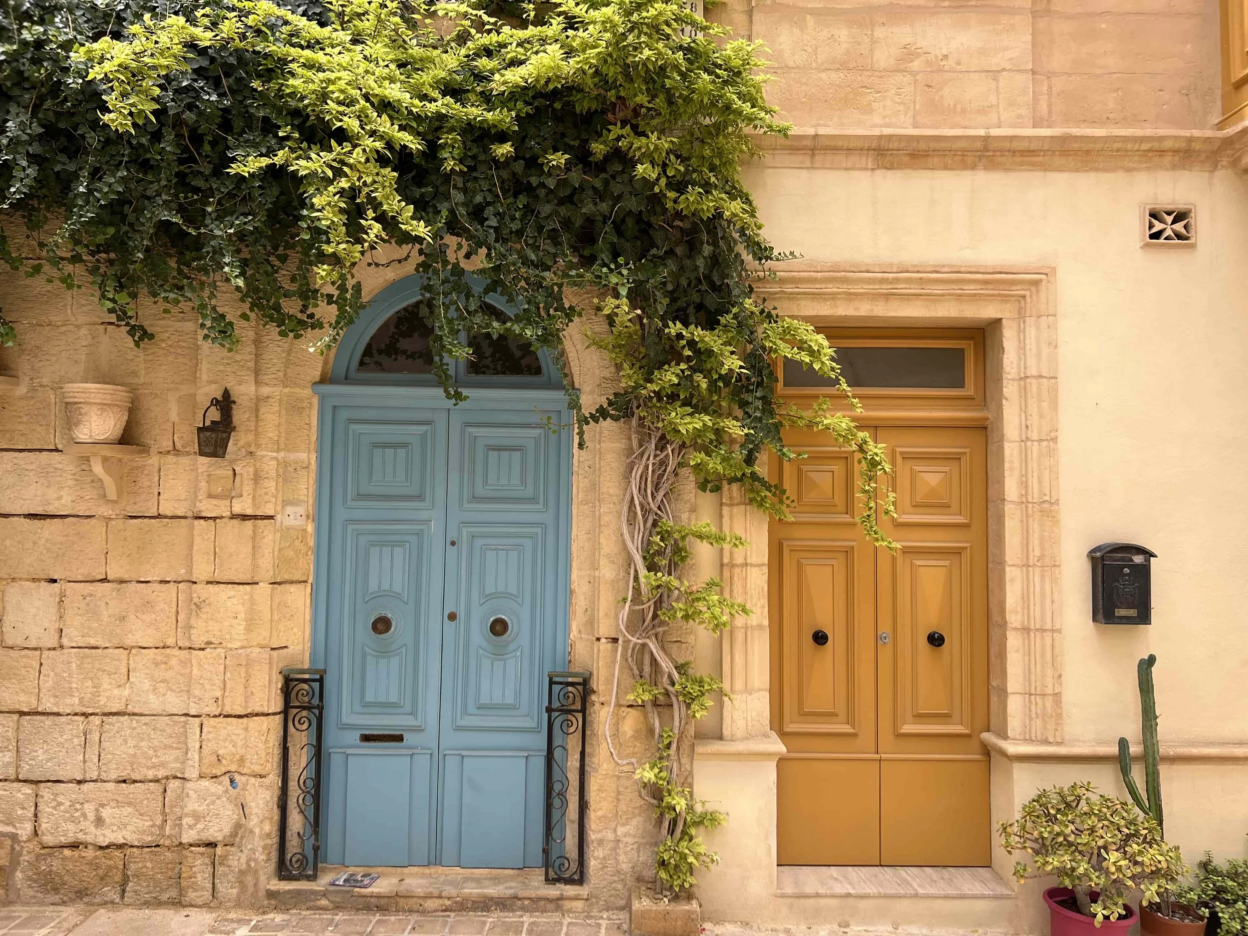 A traditional blue and yellow wooden door in a narrow limestone alley in Birgu (Vittoriosa).