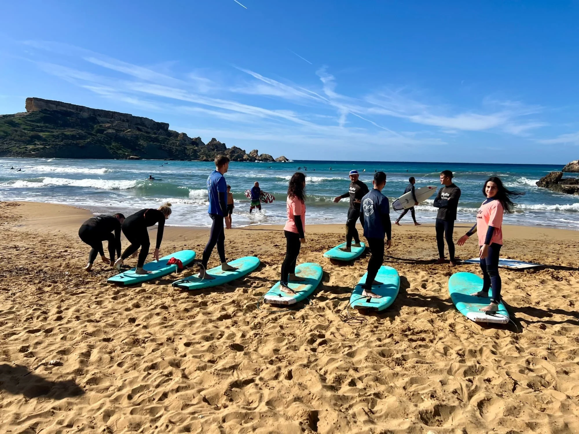 A group of people preparing for a surf lesson on the sand at Riviera Beach.