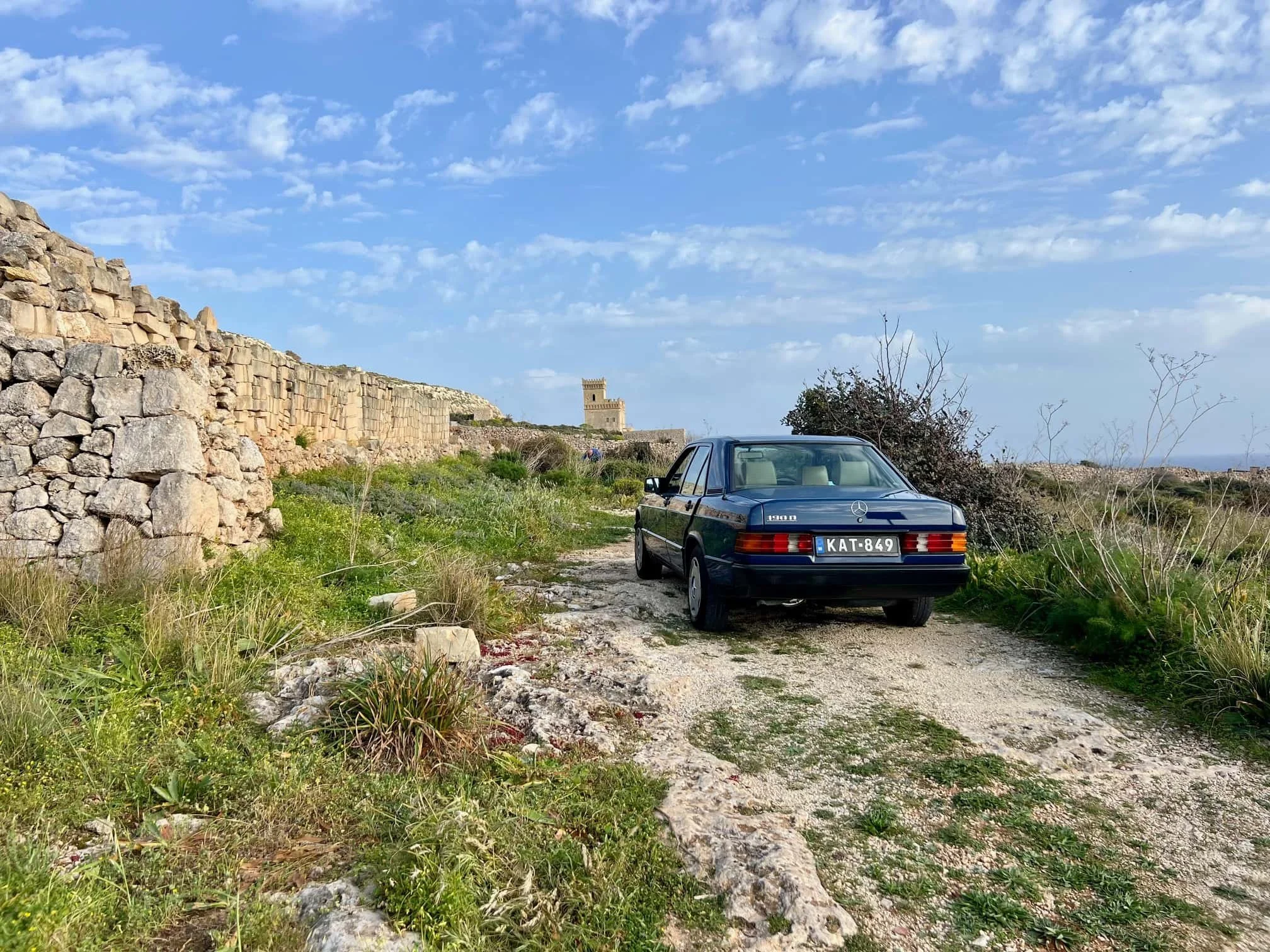 Vintage Mercedes parked on a dirt path along the coastline.