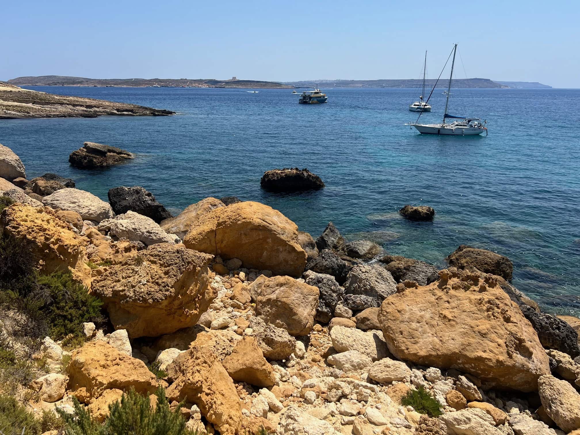 Sailboats anchored in the calm waters of Iz-Zewwieqa Bay near Mgarr Harbour.