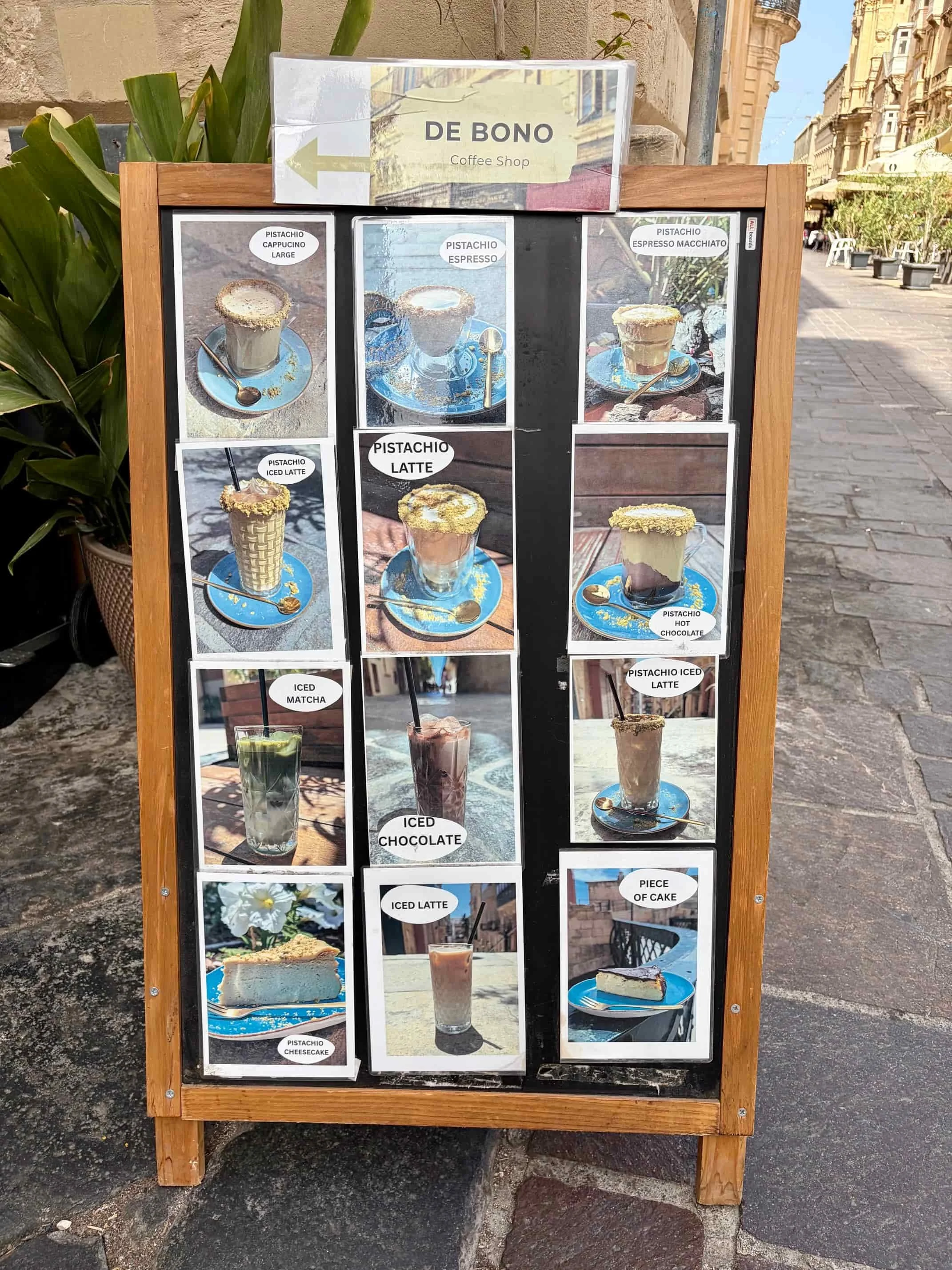 Wooden outdoor stand displaying photos of coffee variety at De Bono Coffee Shop, Valletta.