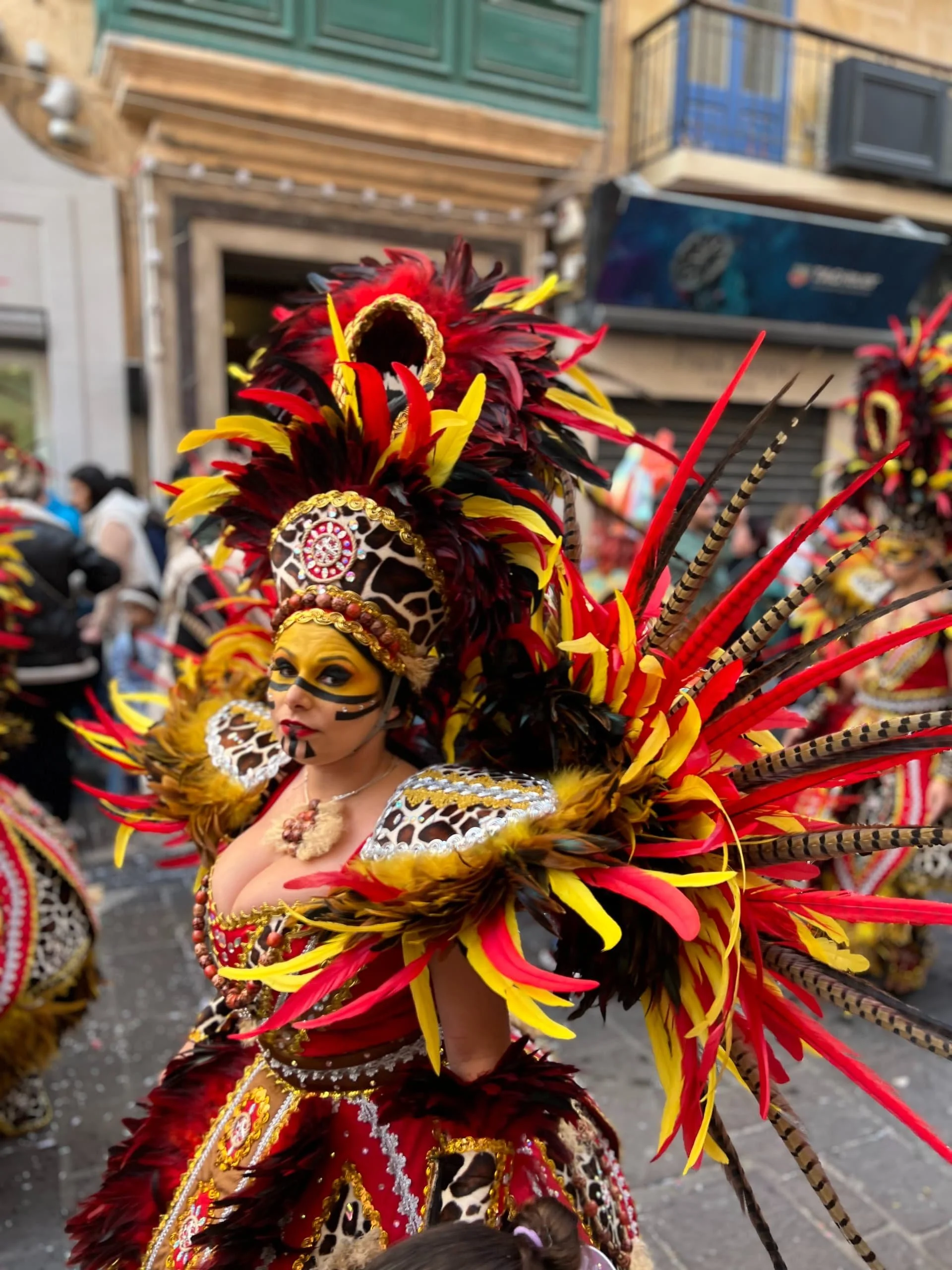 Carnival dancer wearing a red and gold feather costume.