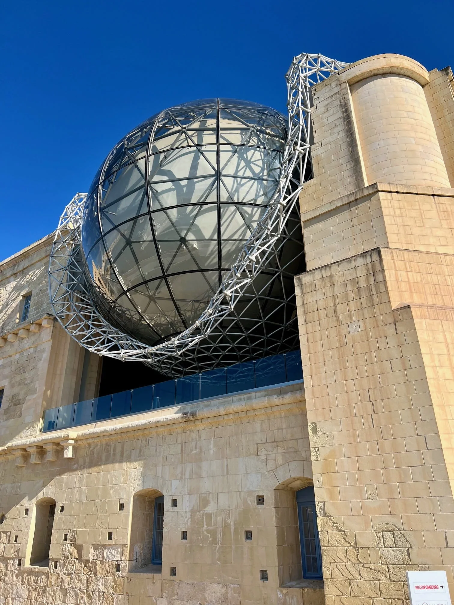 Glass planetarium dome of the Esplora Science Centre set against historic architecture in Kalkara, Malta.