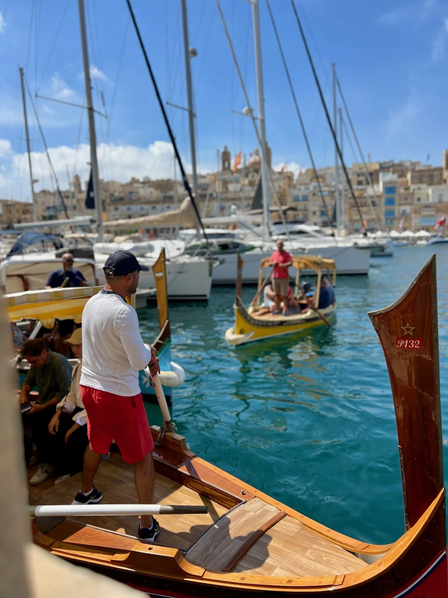A traditional wooden Dgħajsa boat with a gondolier at the Birgu waterfront, Grand Harbour Malta.