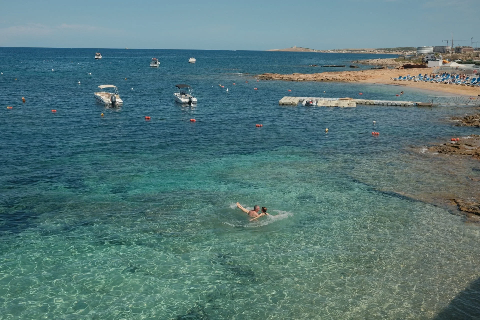 A swimmer enjoying the crystal clear and shallow turquoise water at Mellieha Bay.