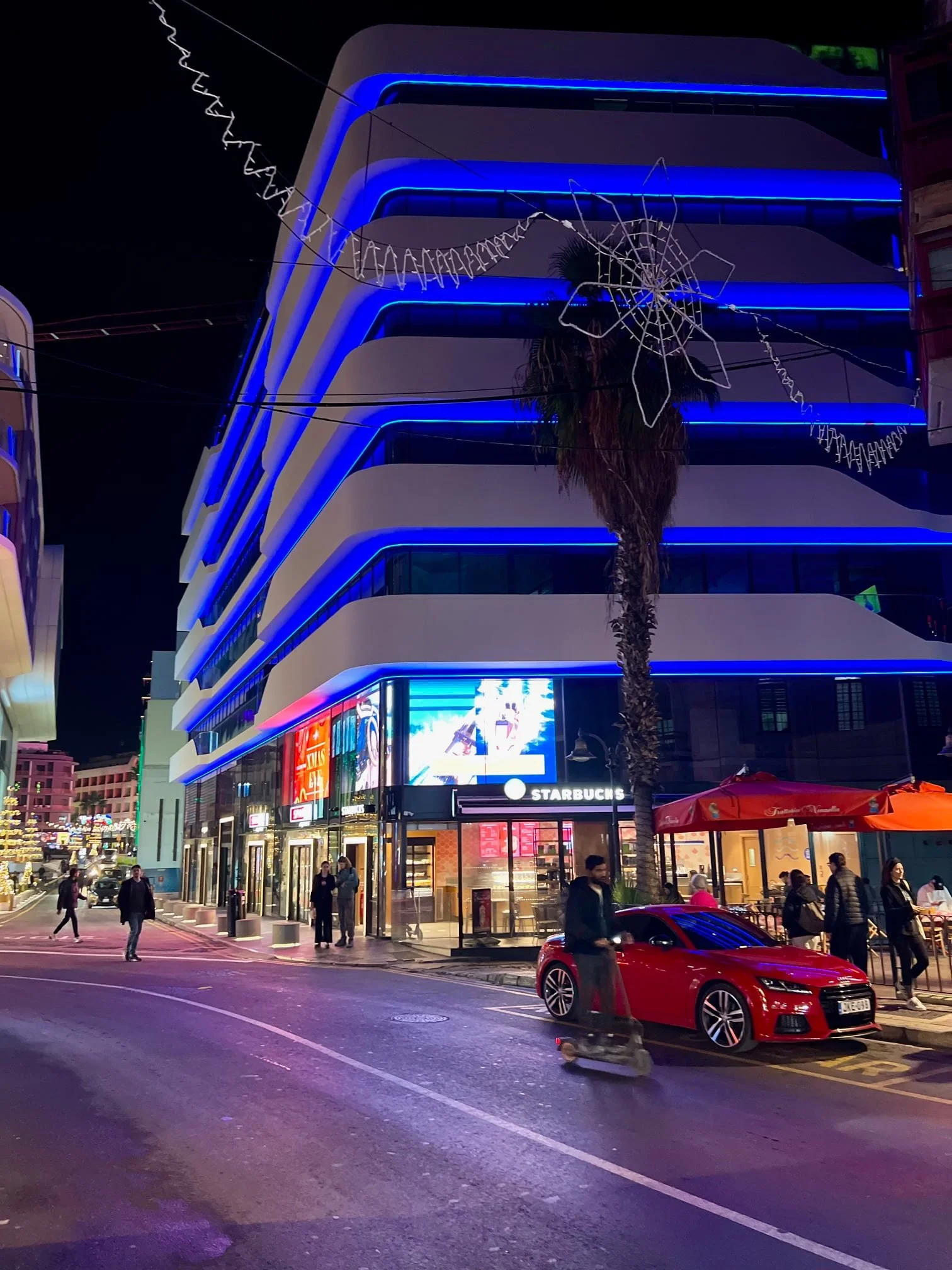 Modern building with blue lighting along St. George's Road in St. Julian's, Malta at night.