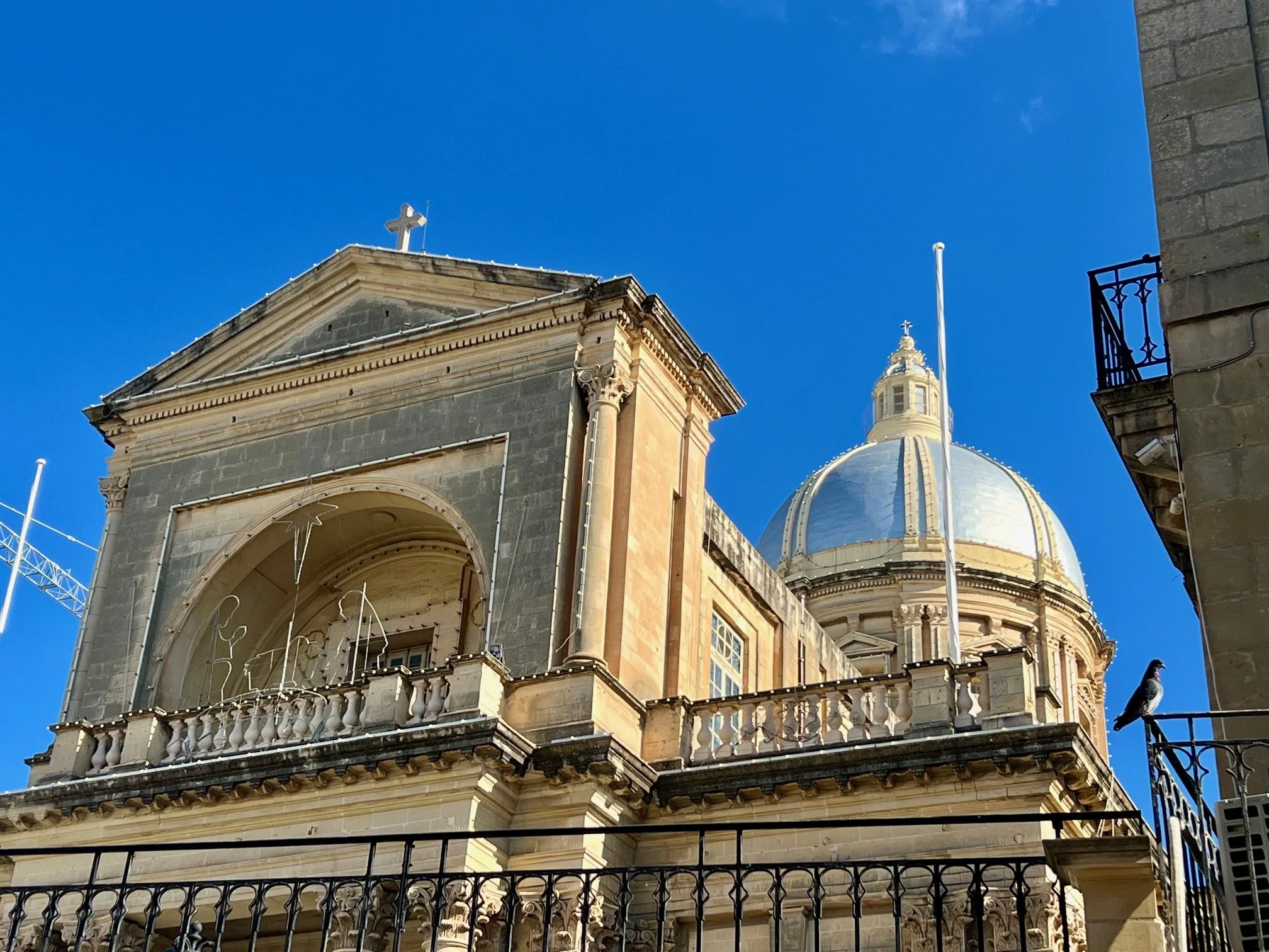 Close-up architectural detail of the Neo-classical facade and limestone cupola of St. Joseph Parish Church in Kalkara.