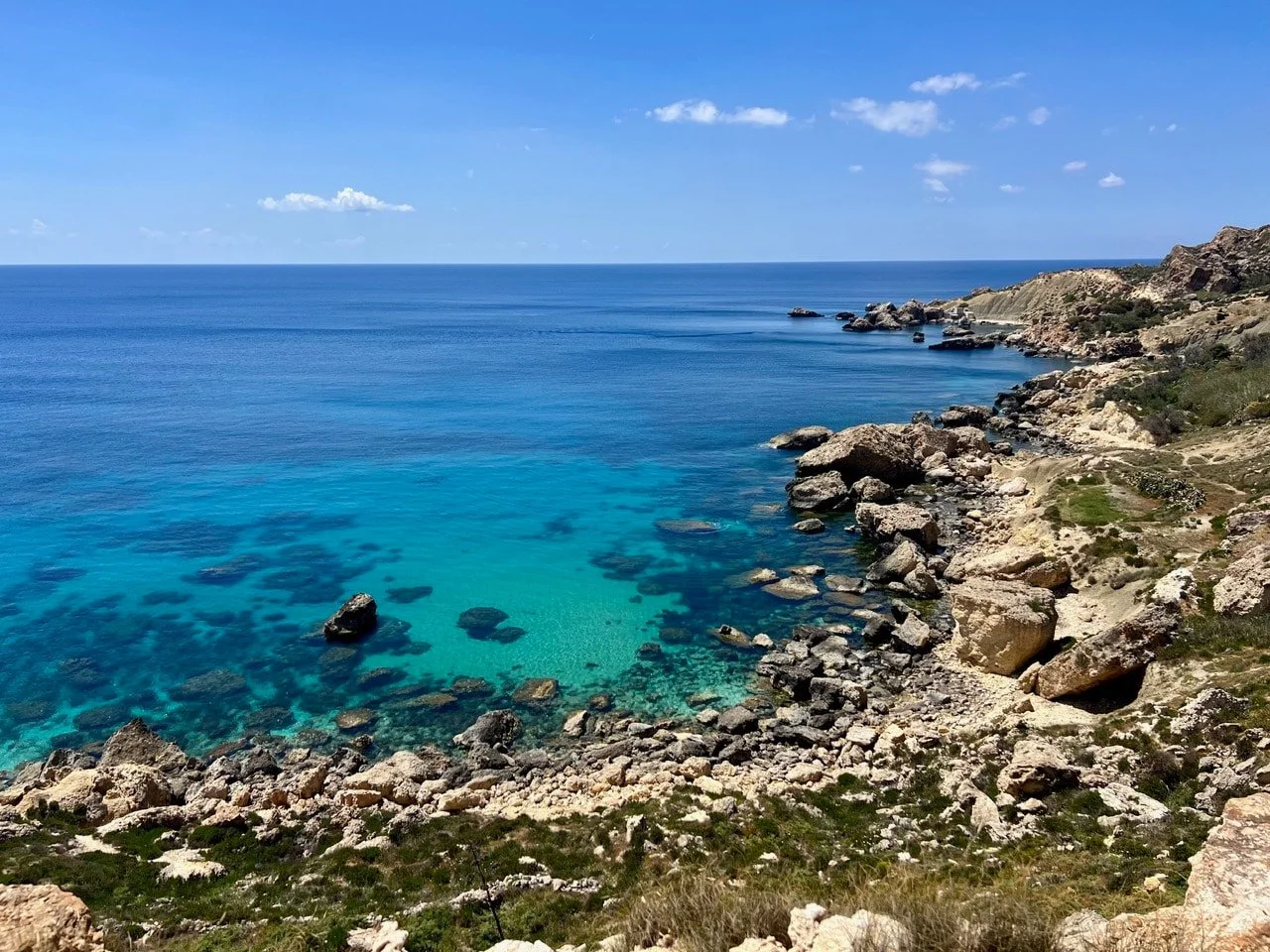 View from the cliff edge down to a bay with turquoise water near Ras il-Wahx.