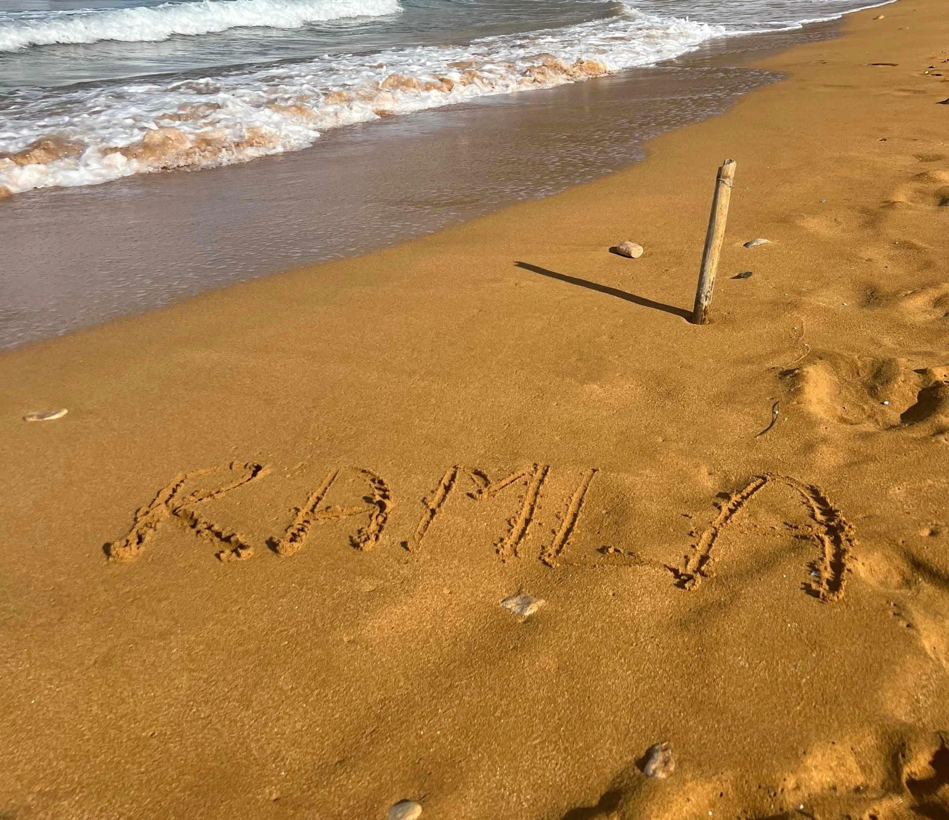 Close up of the unique orange-red sand at Ramla Beach with the word "Ramla" written in it.