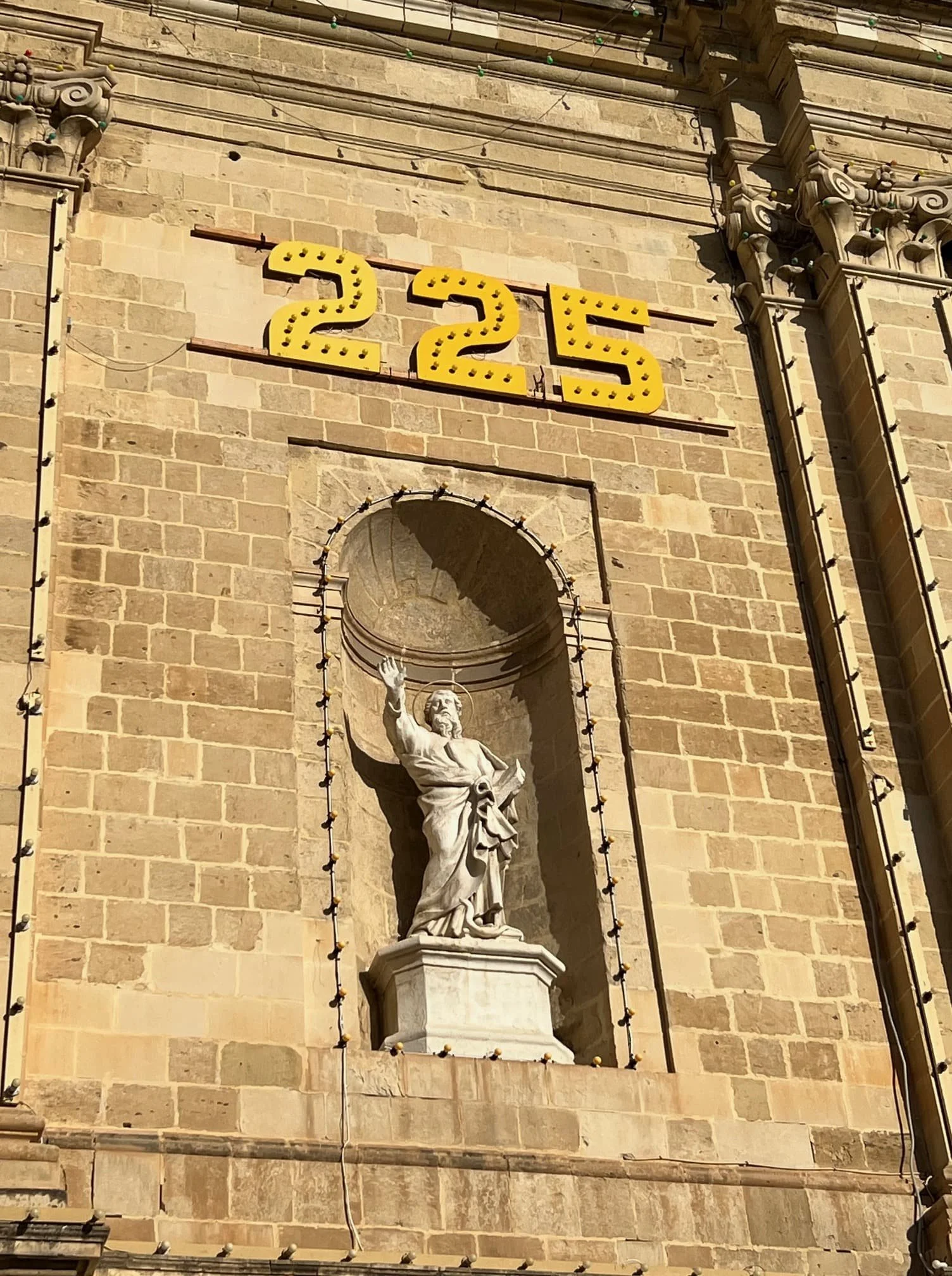 A religious statue integrated into the intricate limestone facade of St. Lawrence Church in Birgu.