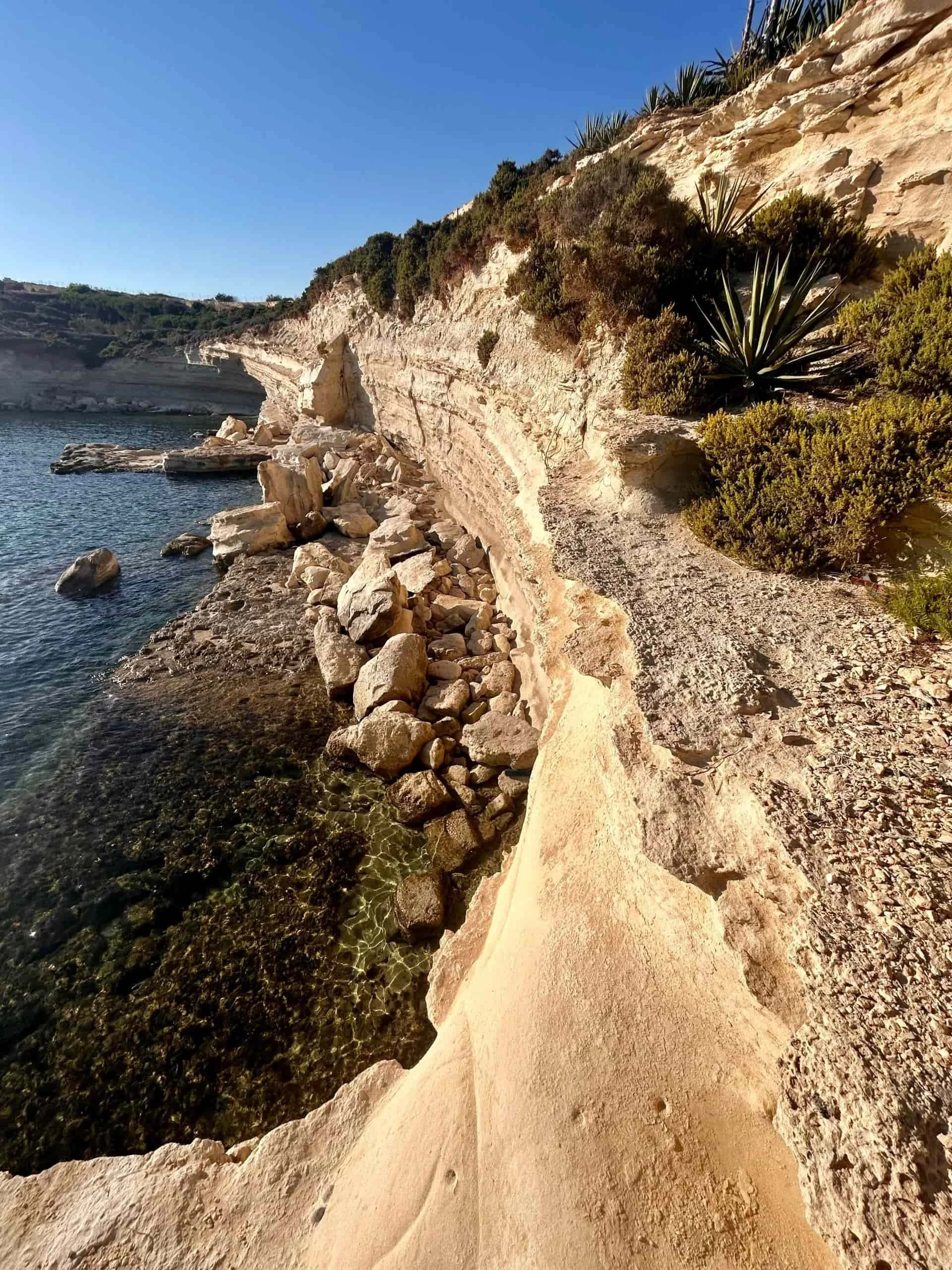 The unique limestone rock formations and rugged coastal path leading to Ta' Kalanka Sea Cave.