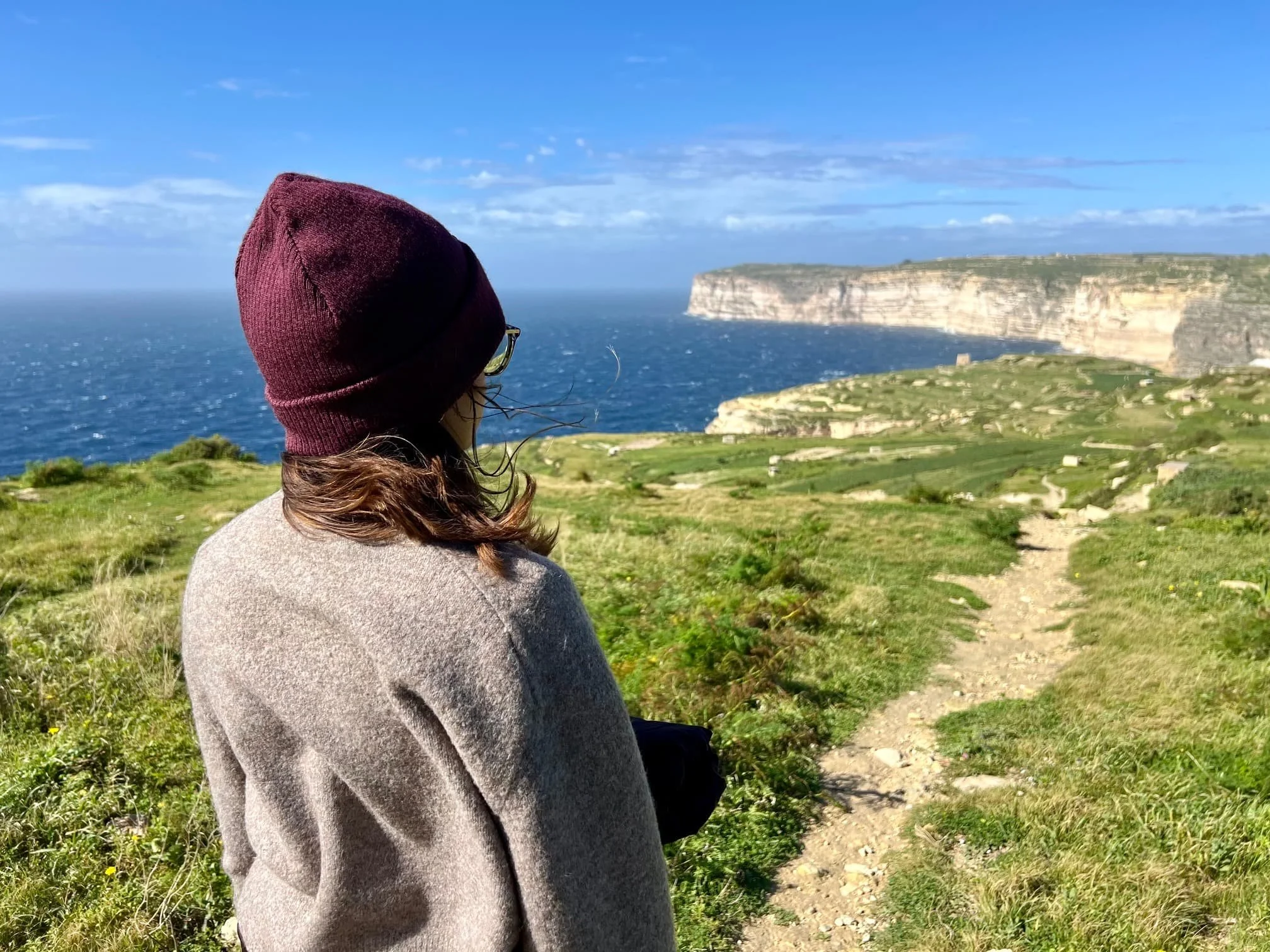 Woman wearing a beanie looking out towards the sea in Gozo during Malta's off-season.
