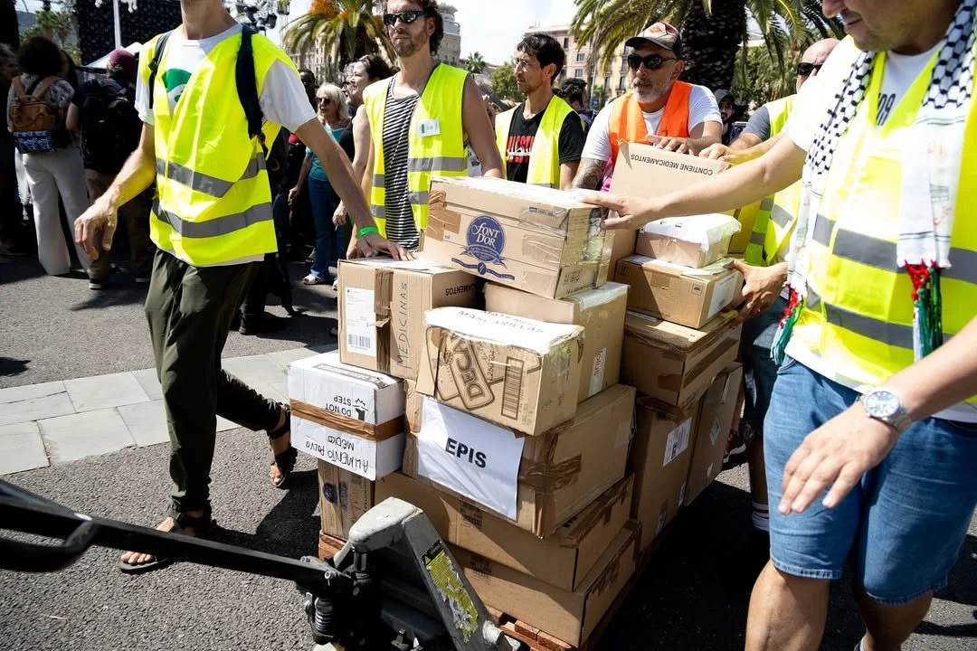 Volunteers loading boxes of humanitarian aid onto ships at the port of Barcelona.
