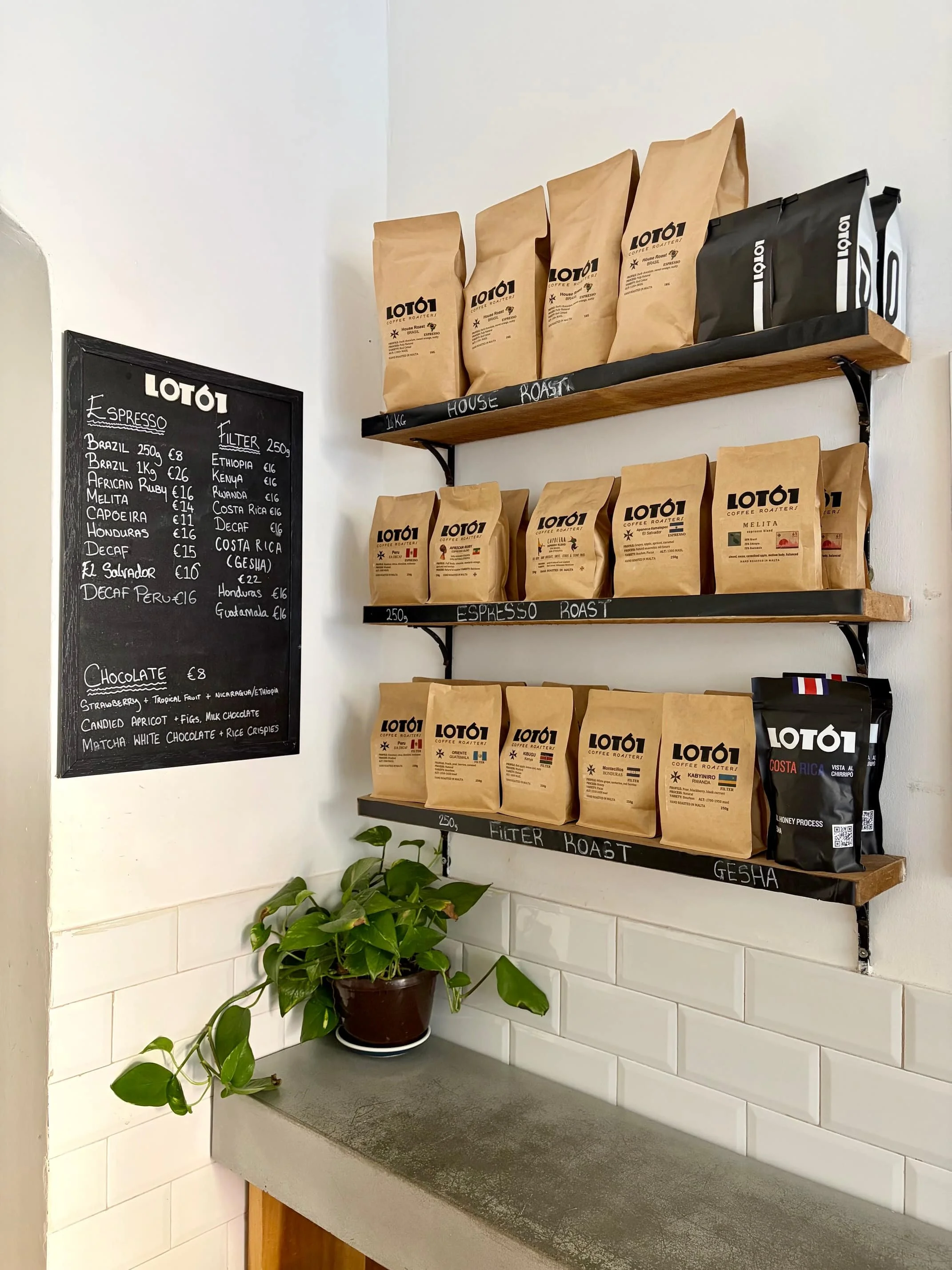 Bags of specialty coffee beans neatly arranged on wooden shelves at Lot61, Valletta.