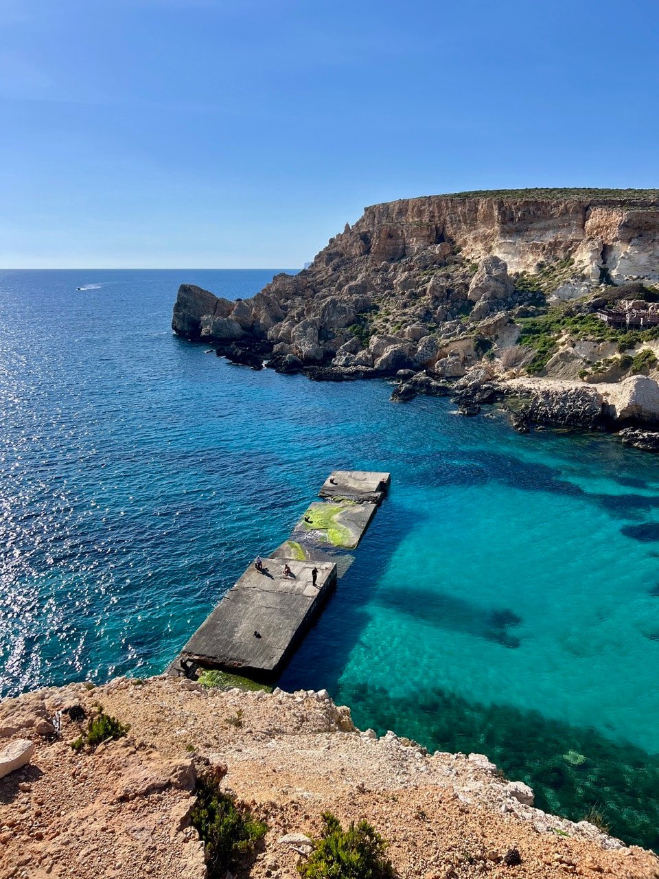Concrete pier extending into the deep turquoise water of Anchor Bay.
