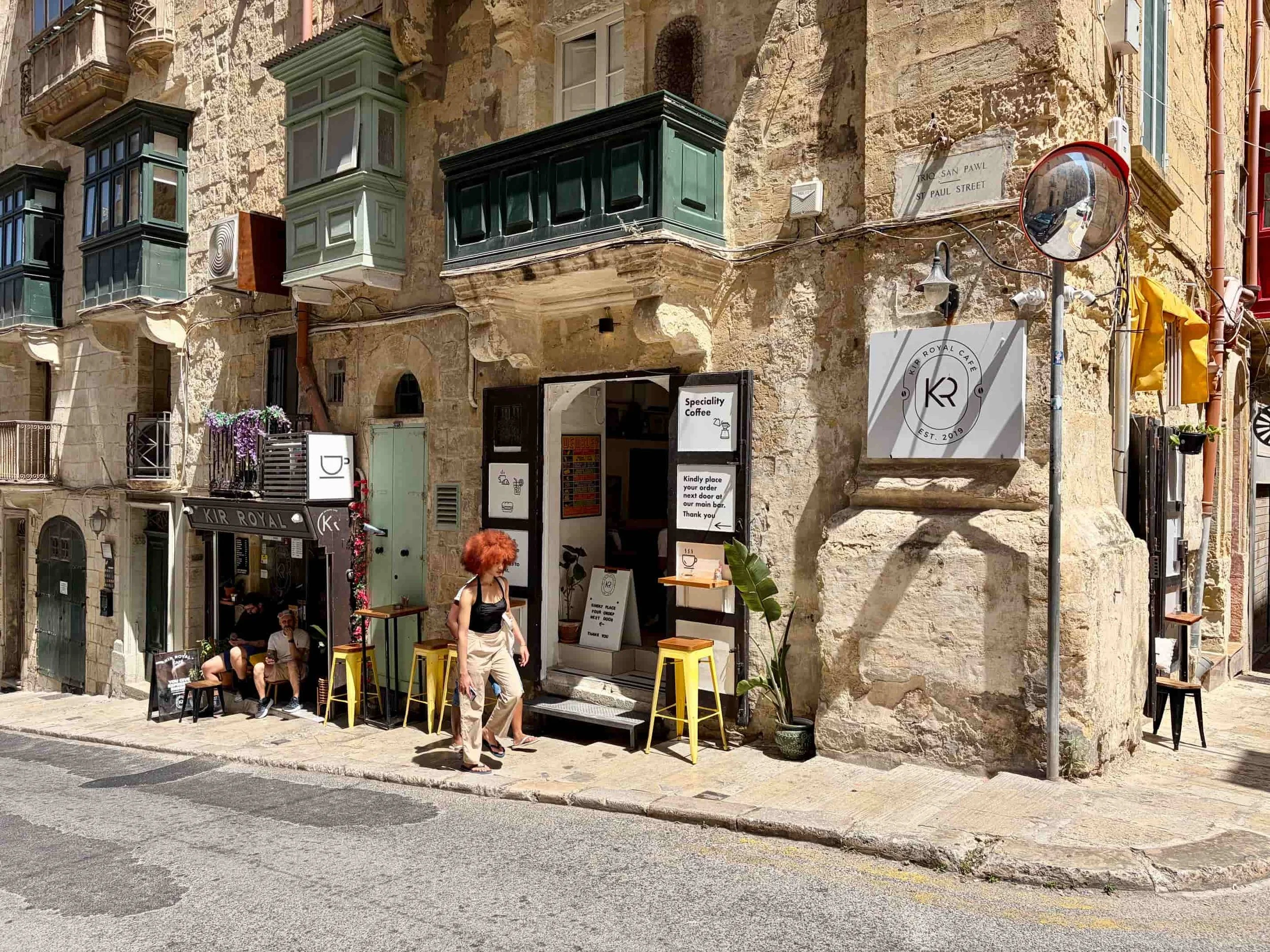 Historic limestone building facade and street view in front of Kir Royal Café, Valletta.