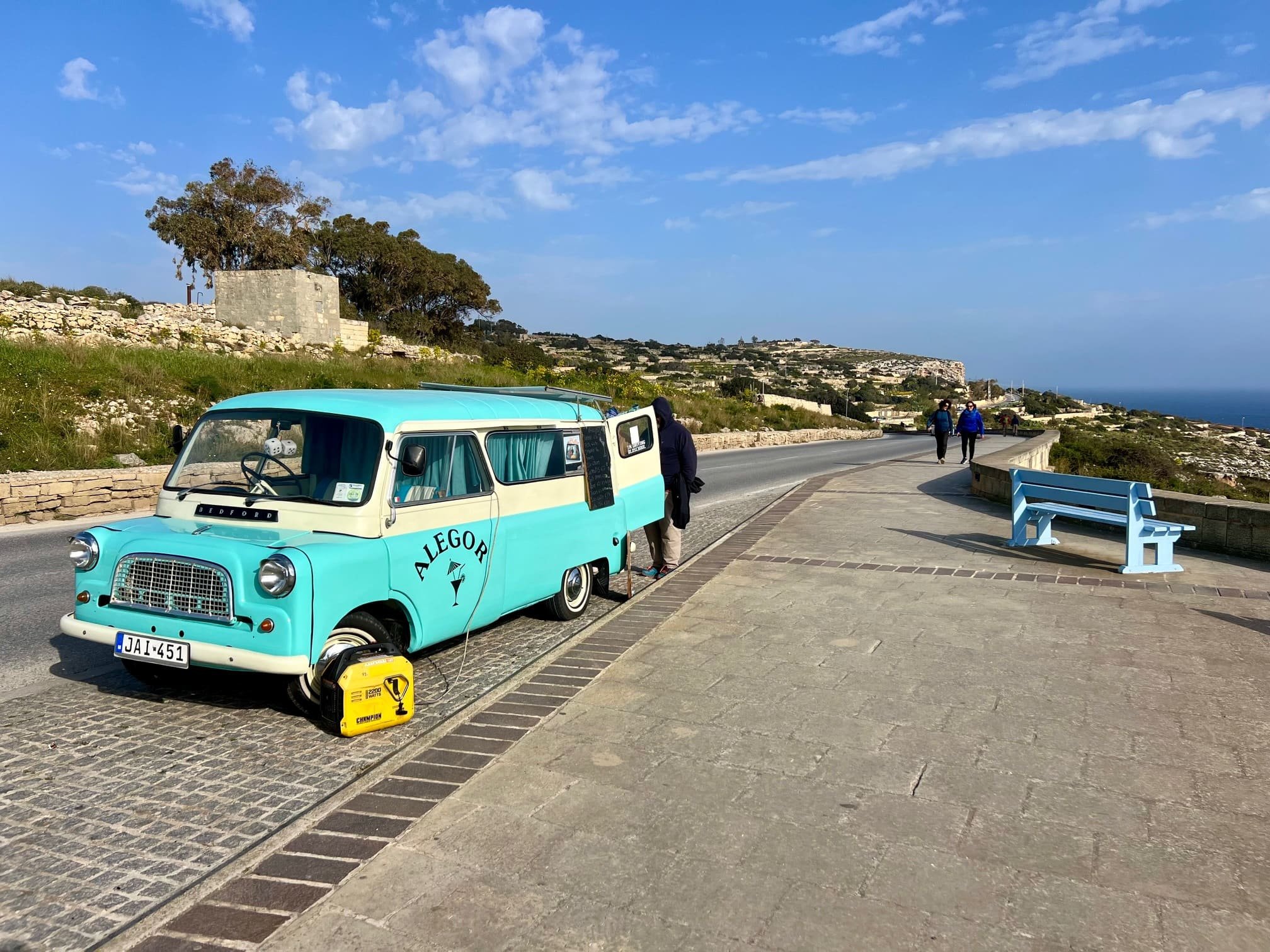 Light blue vintage van parked along the coastal road in Malta.