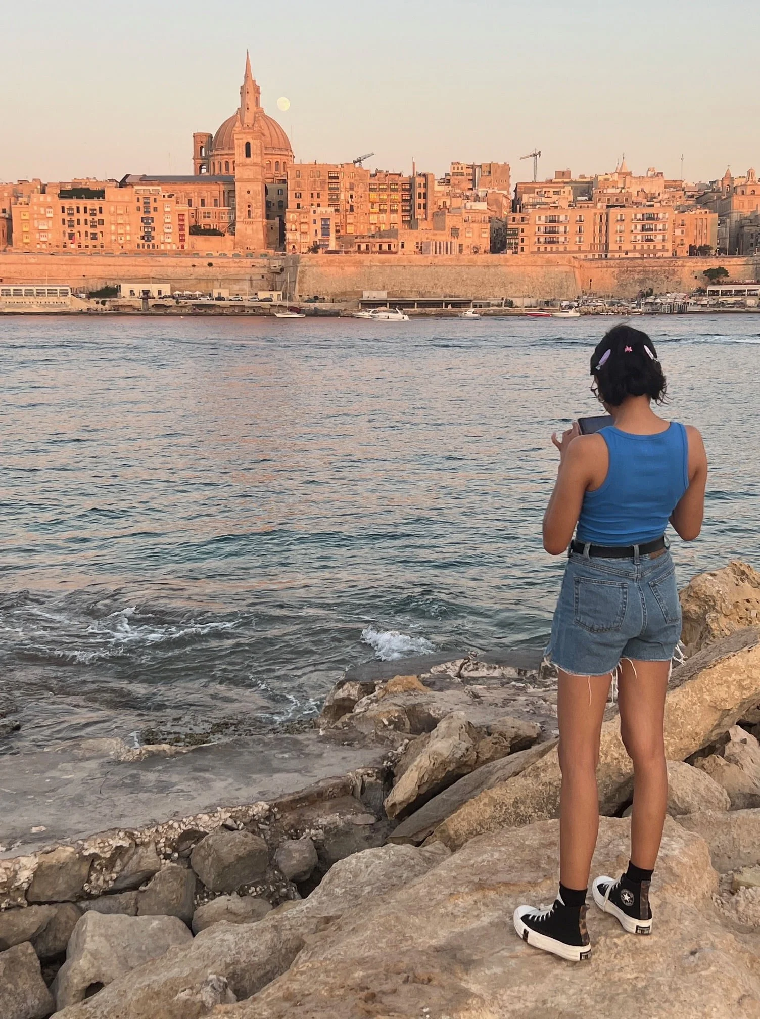 Woman enjoying the sunset view over the Valletta skyline from Manoel Island in Gzira.