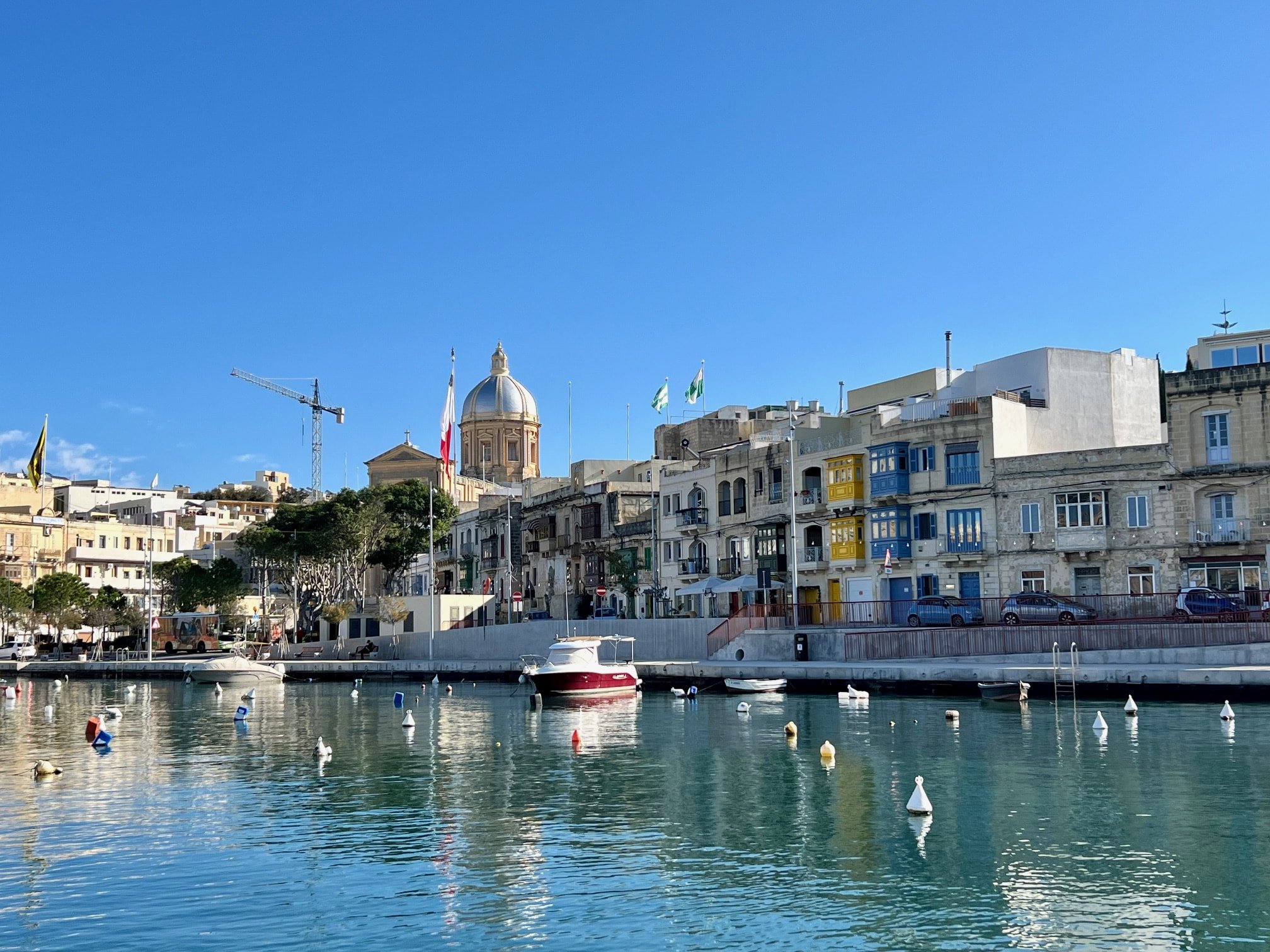 Traditional Maltese townhouses with colorful wooden balconies along the waterfront in Kalkara.