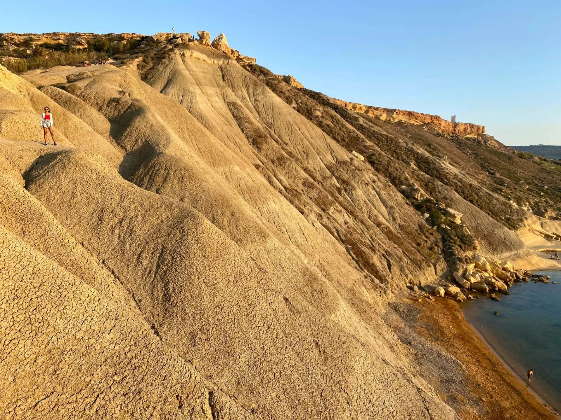 The unique brown and orange clay slopes and rock formations surrounding Gnejna Bay.