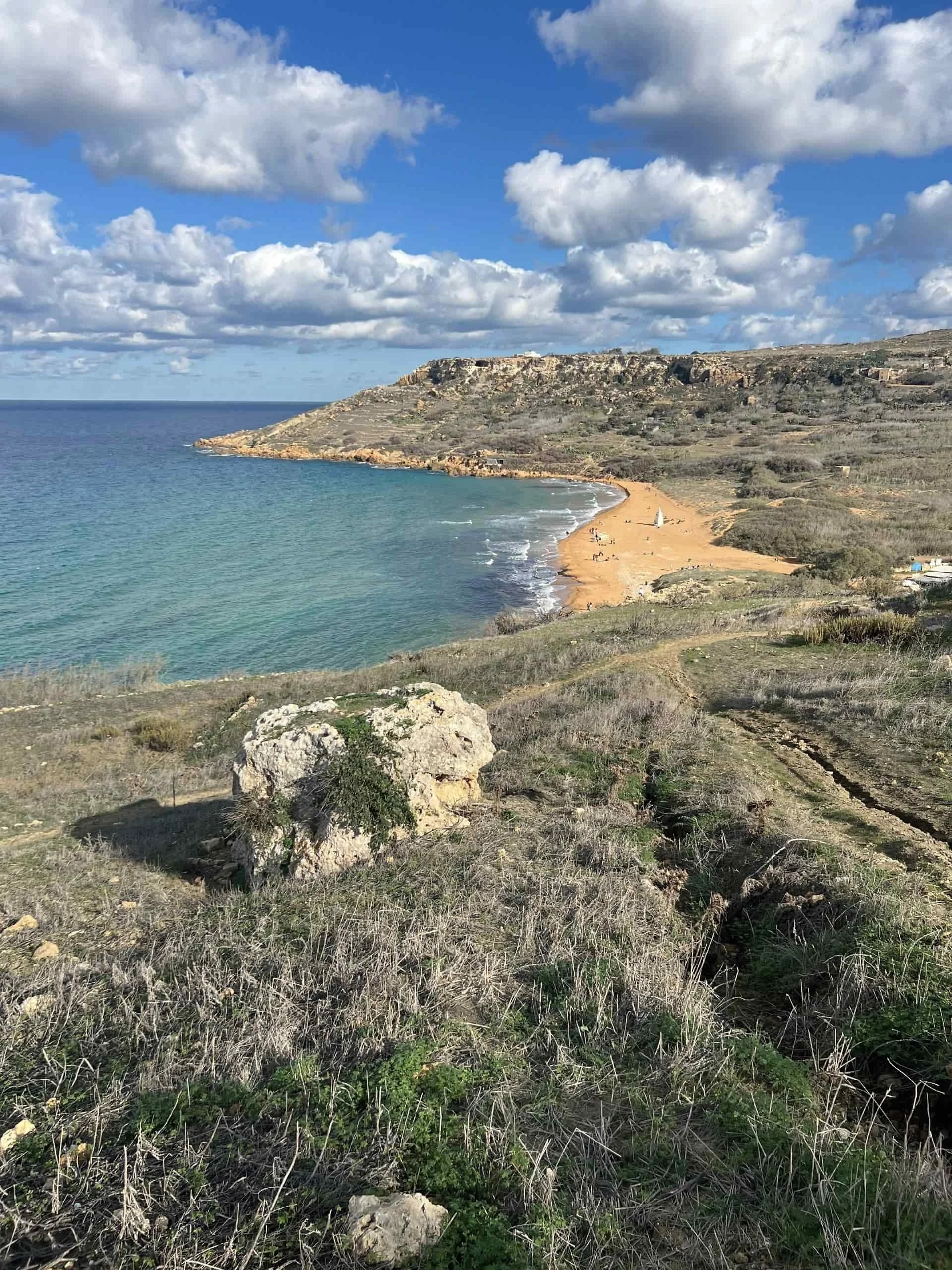 A coastal hiking path overlooking the turquoise sea and golden-red coastline of Ramla Bay.