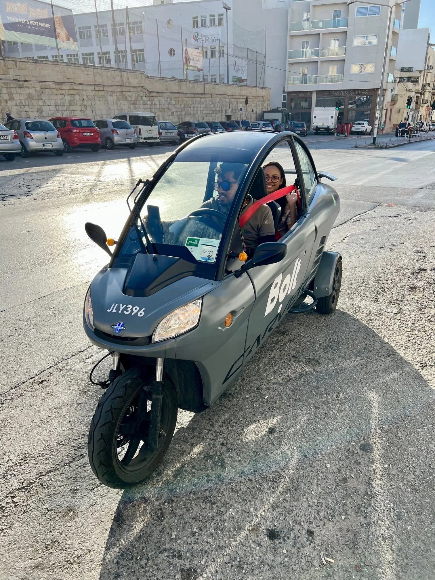 A small grey Bolt Lite vehicle (Carver) with a passenger, leaving from Gzira, Malta.