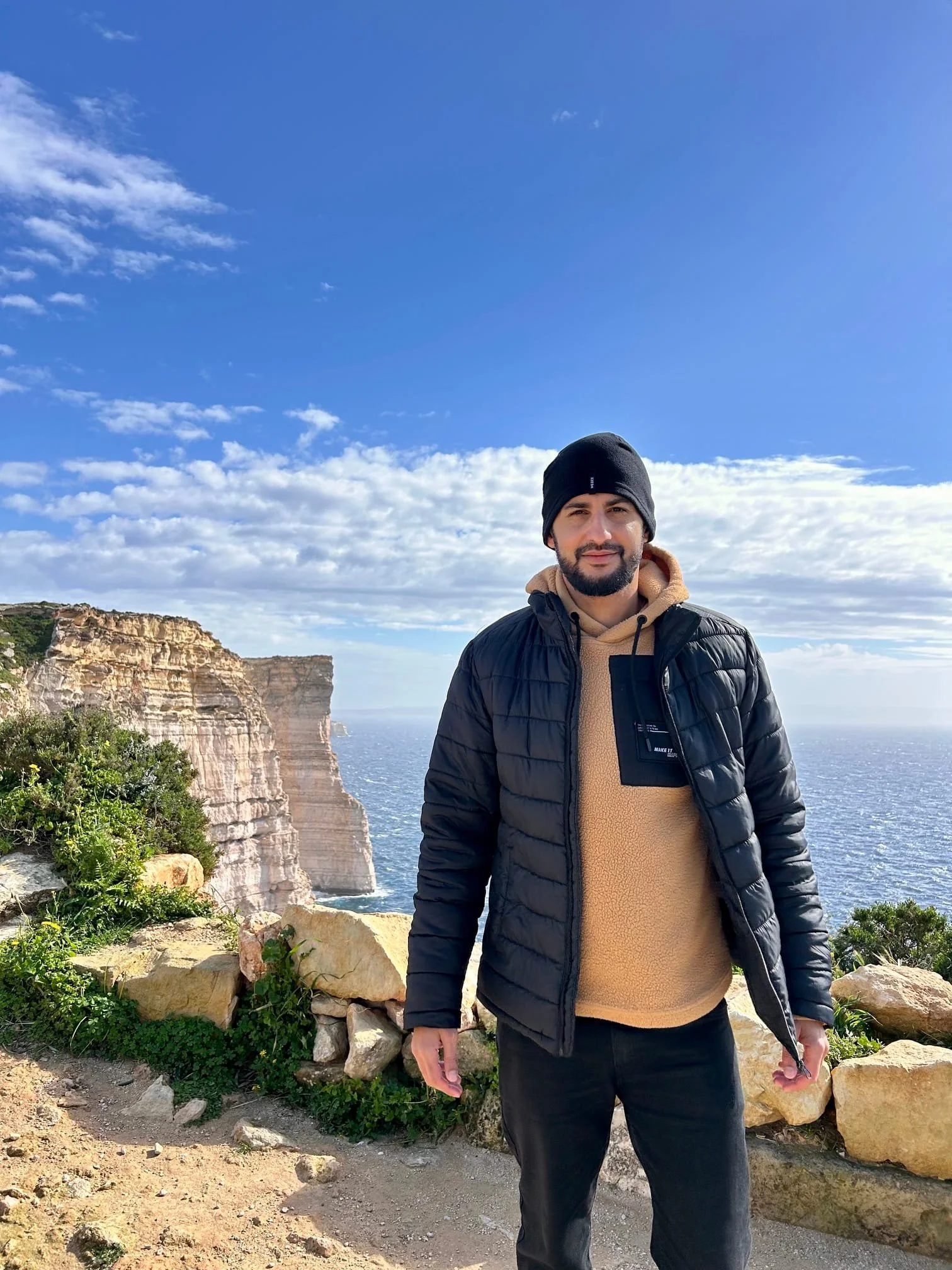 Man standing on a coastal path overlooking Sanap Cliffs and the sea in Gozo in January..
